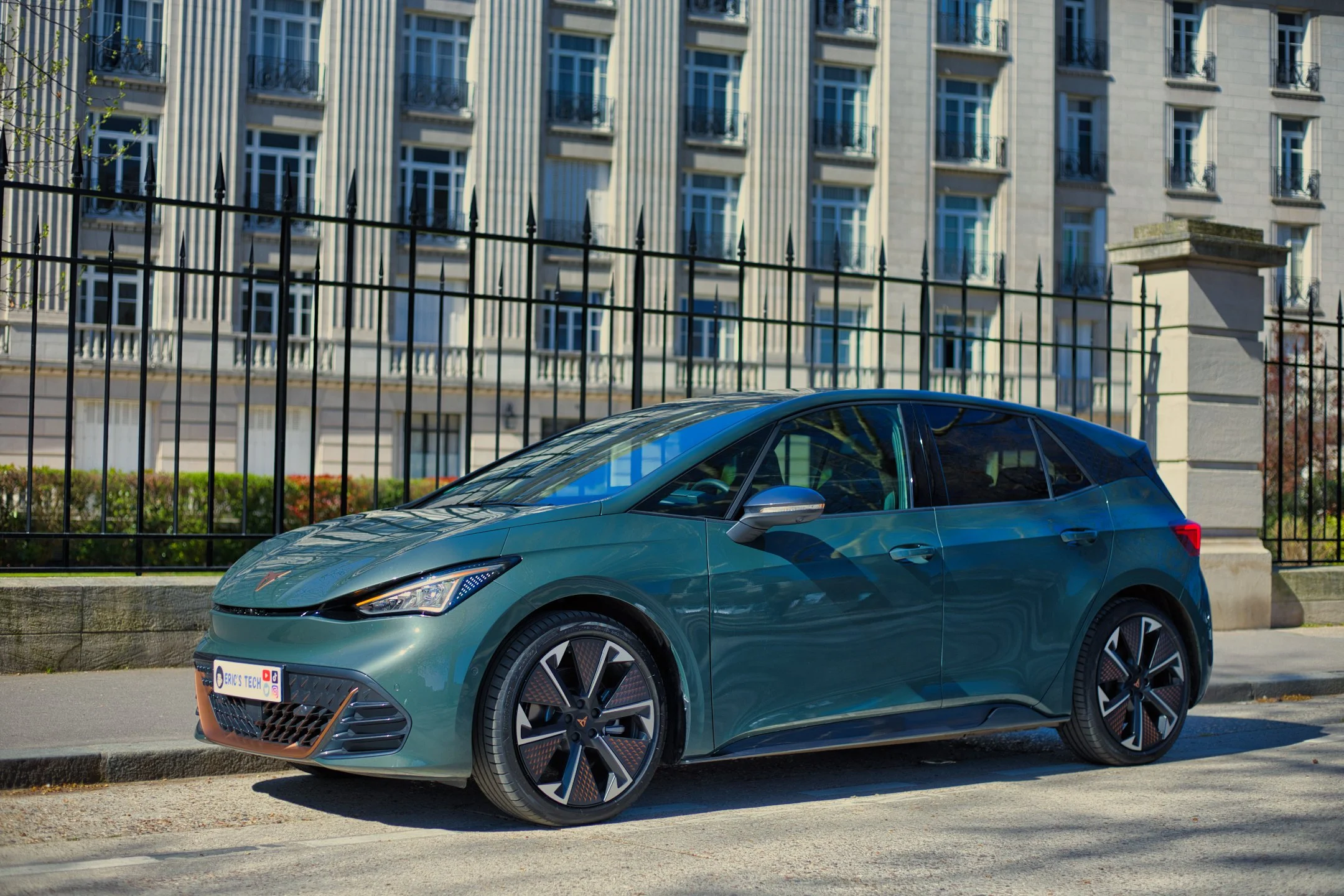 Cupra Born VZ verte garée sur la voie en ville avec un bâtiment résidentiel en arrière-plan.