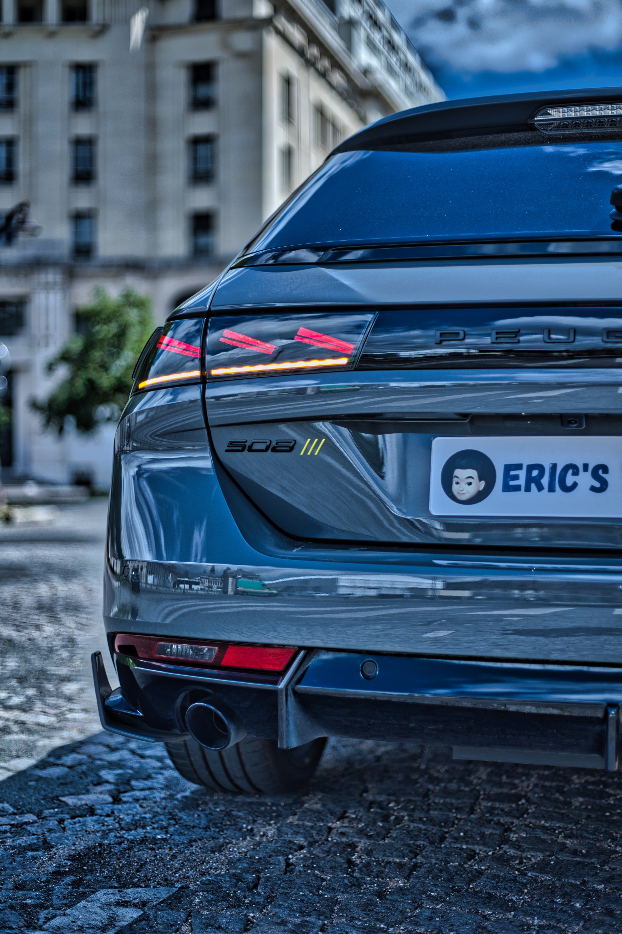 Vue partielle d'une voiture Peugeot, modèle 508SW PSE, avec un casque de stationnement personnalisé indiquant "Eric's" et un logo de personnage animé.