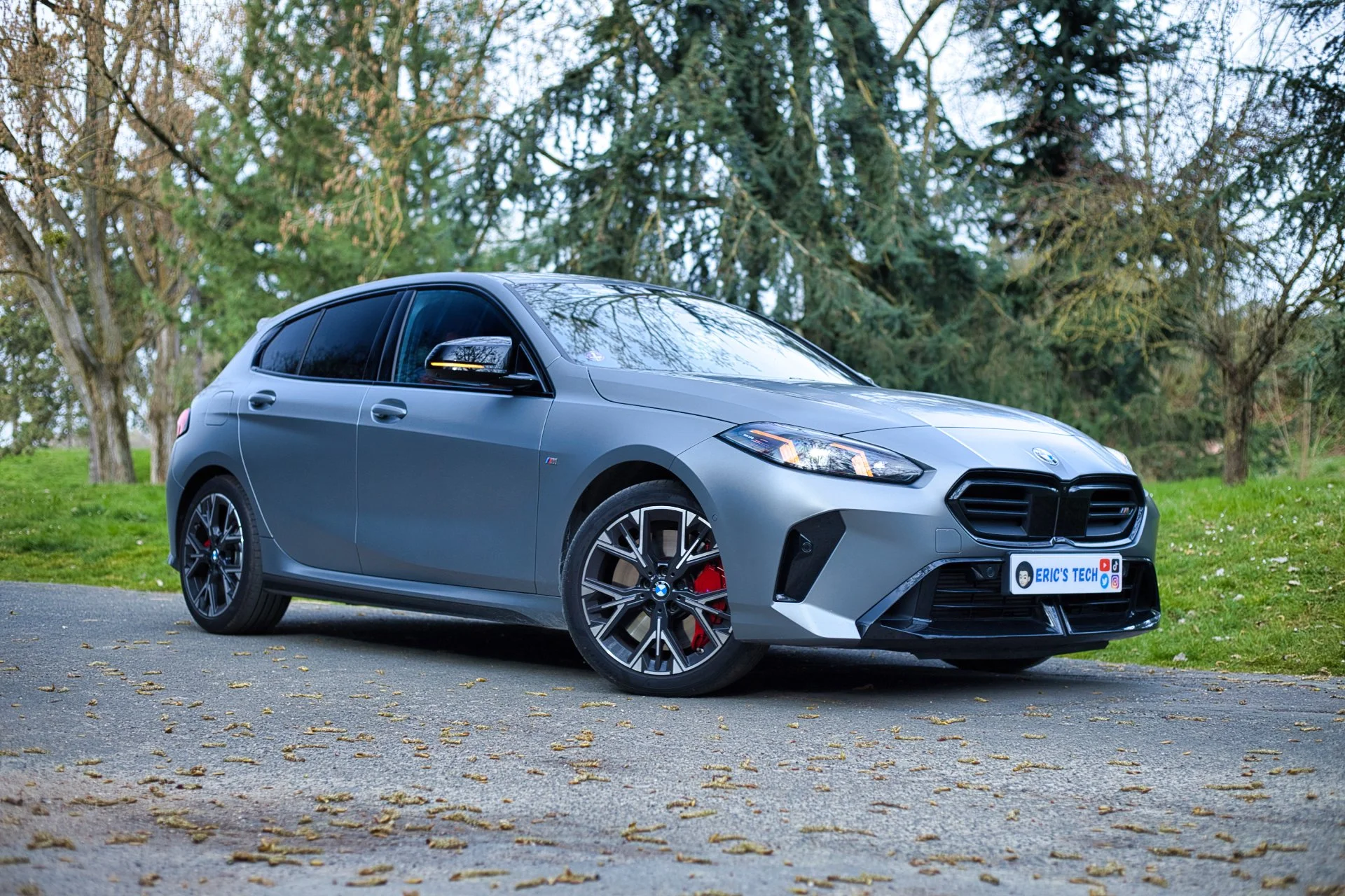 Voiture BMW grise arrêtée sur un chemin en plein air avec des arbres en arrière-plan.
