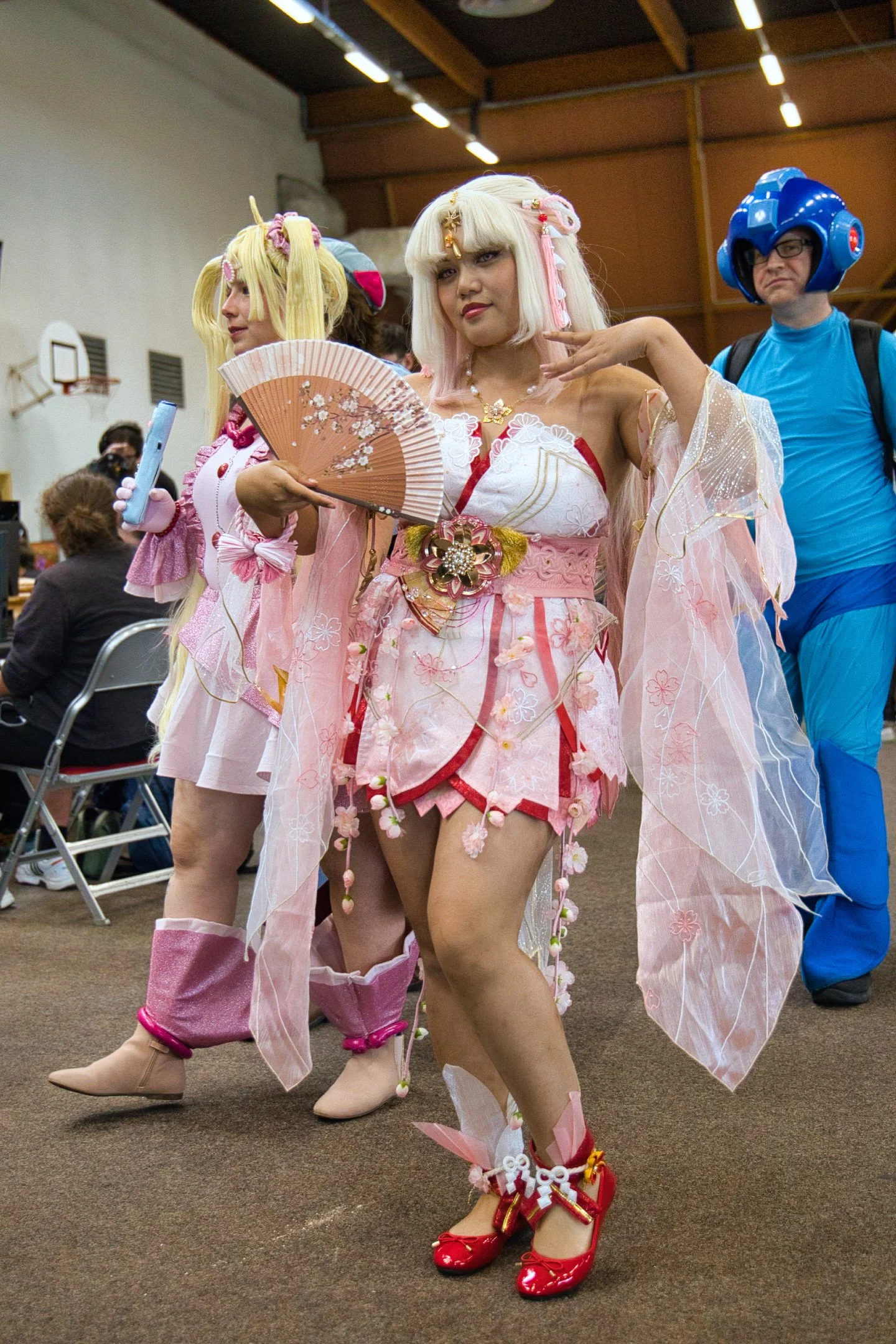 Personnes en costumes de cosplay, une femme en costume rose avec un éventail japonais, et un homme en costume bleu avec un casque pixelisé, lors l'évènement Gaming Théodasium à Thiais