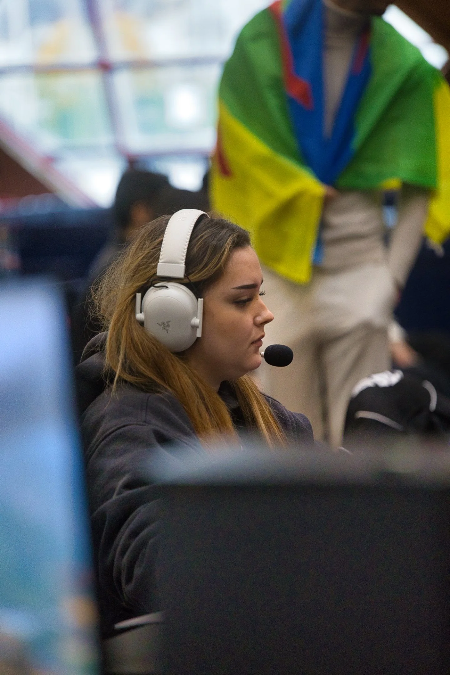 Une jeune femme portant un casque audio avec micro, concentrée, lors de l'évènement Gaming Théodasium 2025 à Thiais