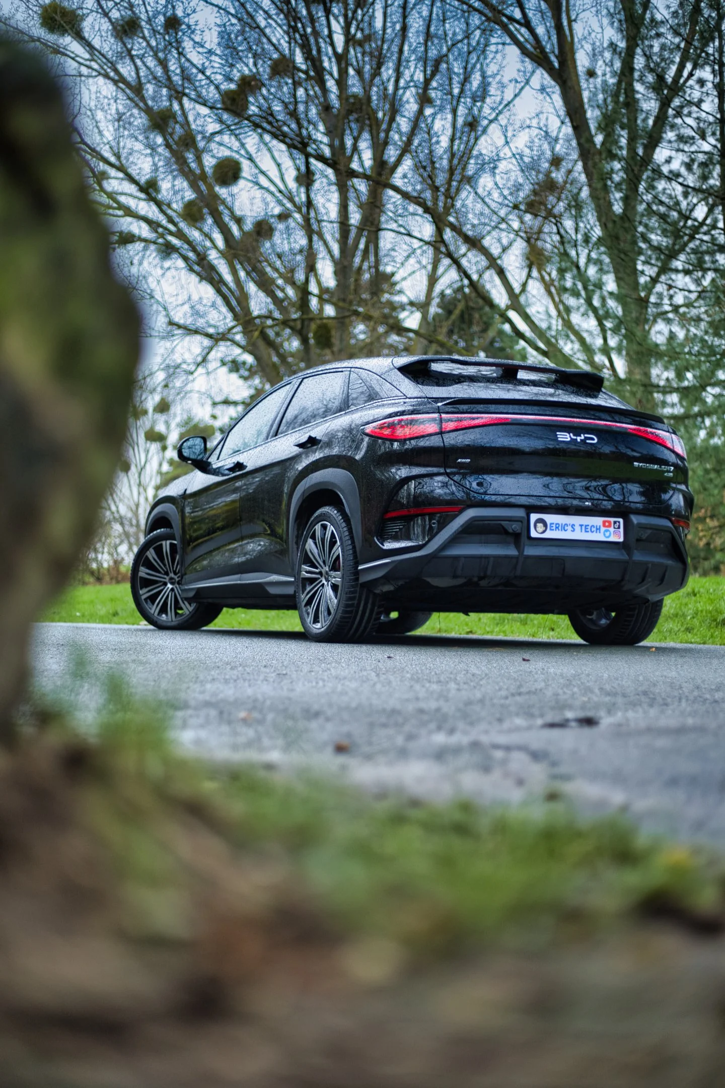 BYD Sealion 7 stationnée sur une route dans un environnement naturel avec des arbres sans feuilles en arrière-plan.