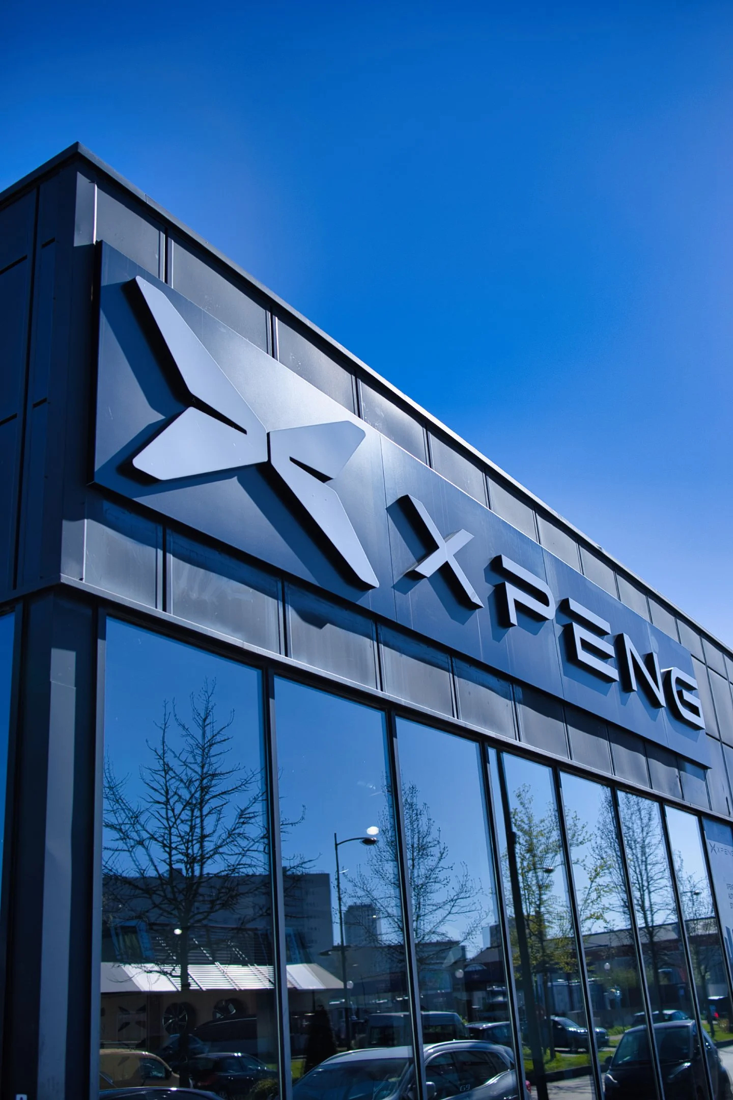 Façade d'un bâtiment avec le logo Xpeng, représentant le constructeur automobile Xpeng, sous un ciel bleu.