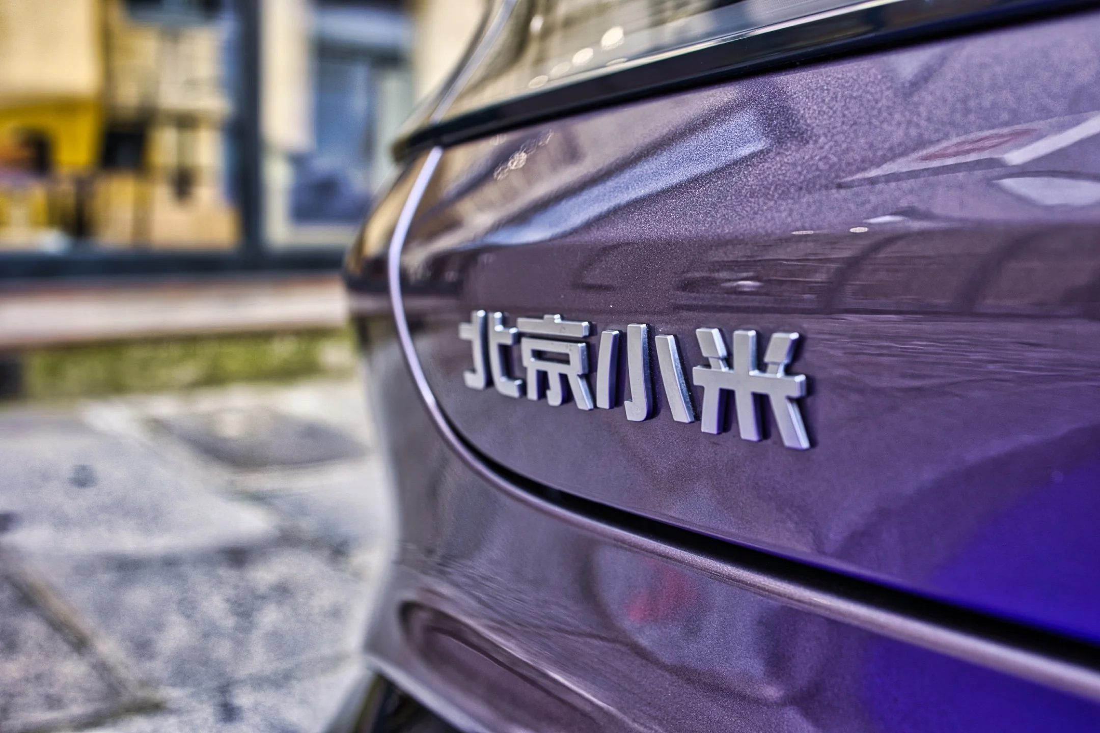 Xiaomi SU7 Max Zoom sur une voiture violette avec une badge en caractères chinois.