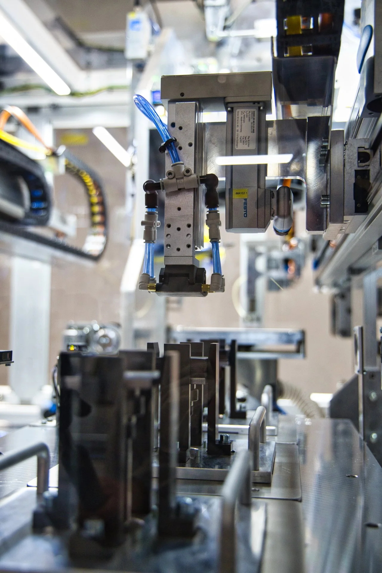 Une machine automatisée dans une usine, avec des composants métalliques et des tubes en plastique bleus.
