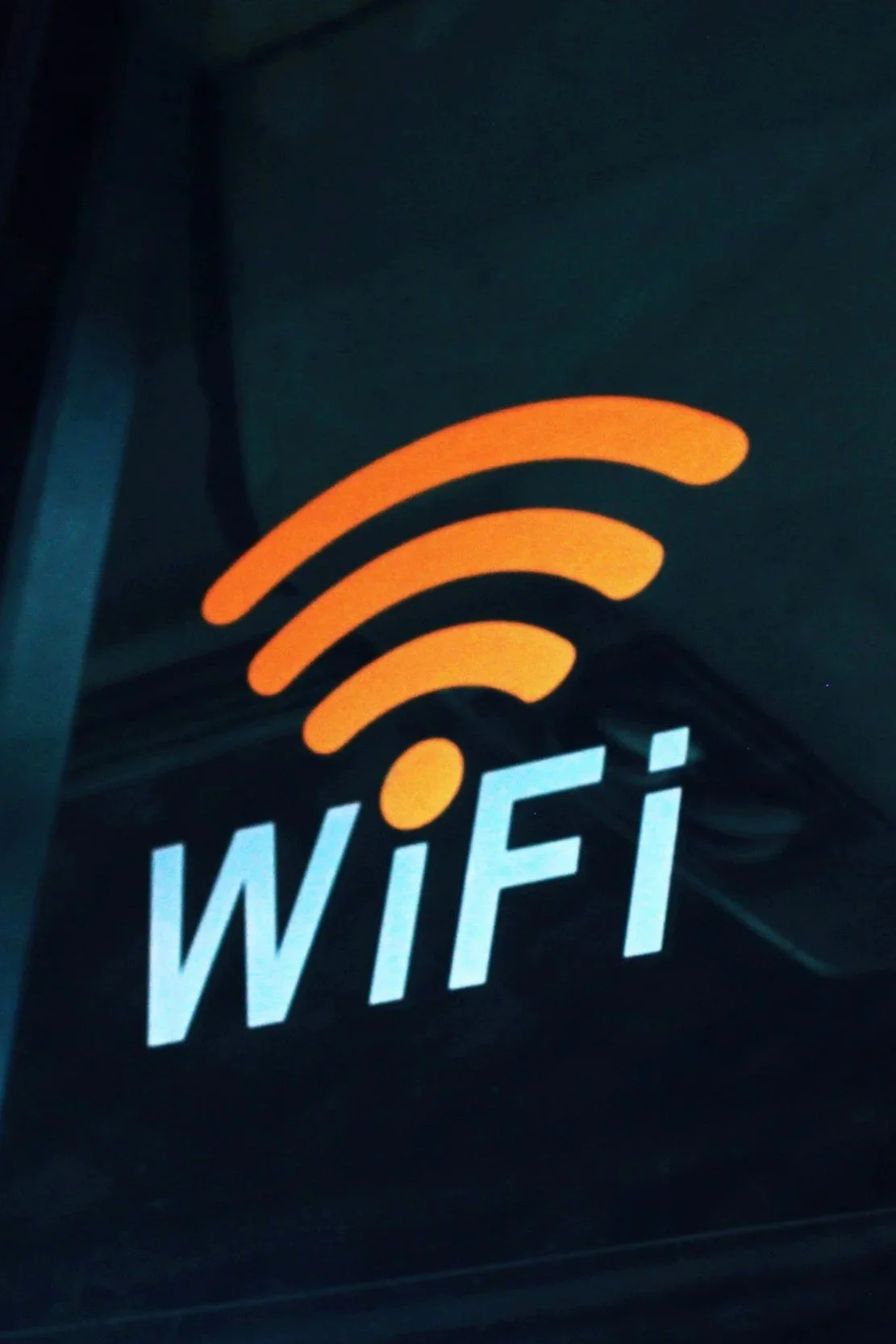 Illuminated Wi-Fi sign with orange signal waves above the word 'WiFi' in white letters.