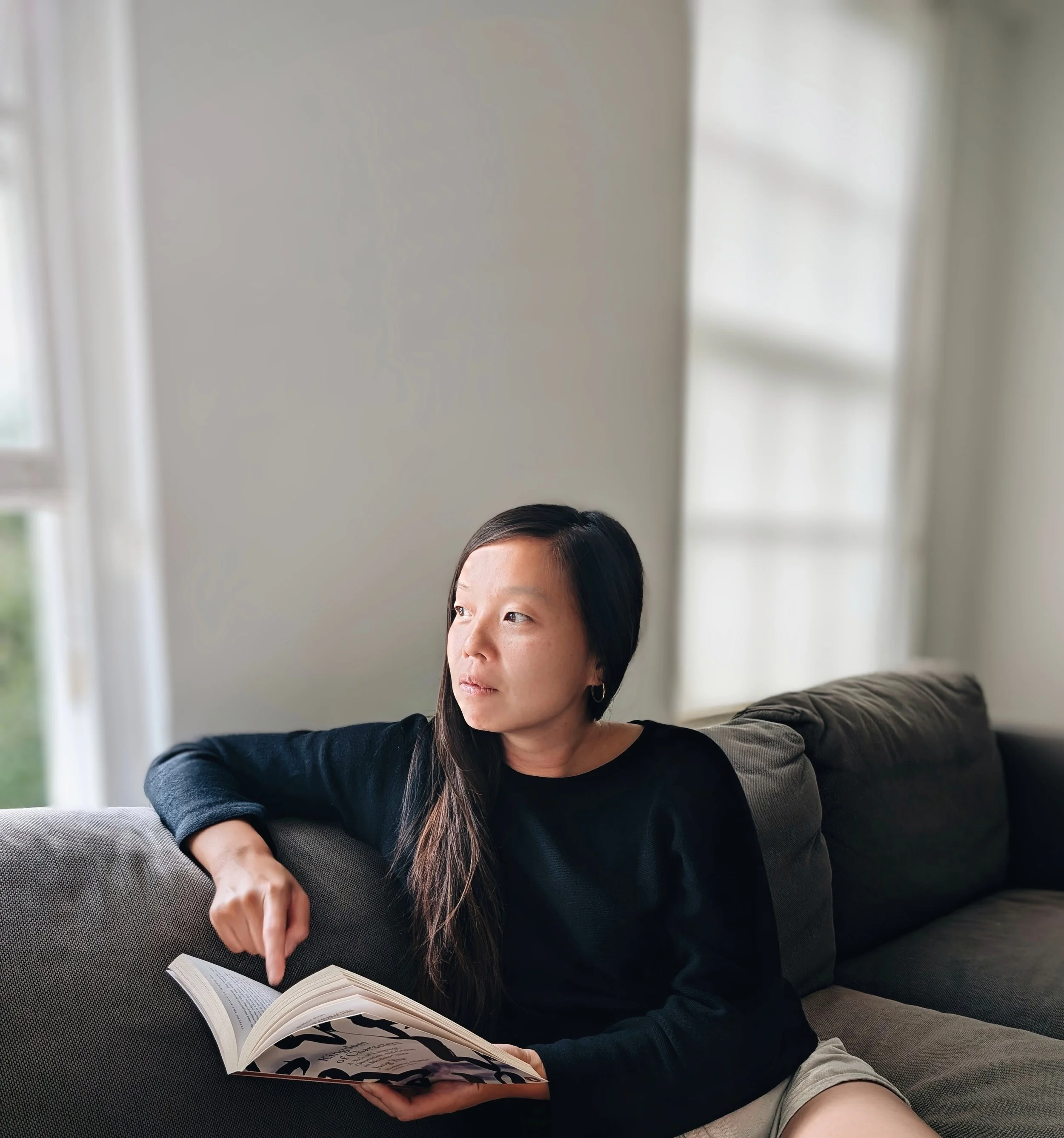 Portrait of the founder of Small Talk of China in a bright, modern London studio, thoughtfully reviewing a Mandarin linguistics book.