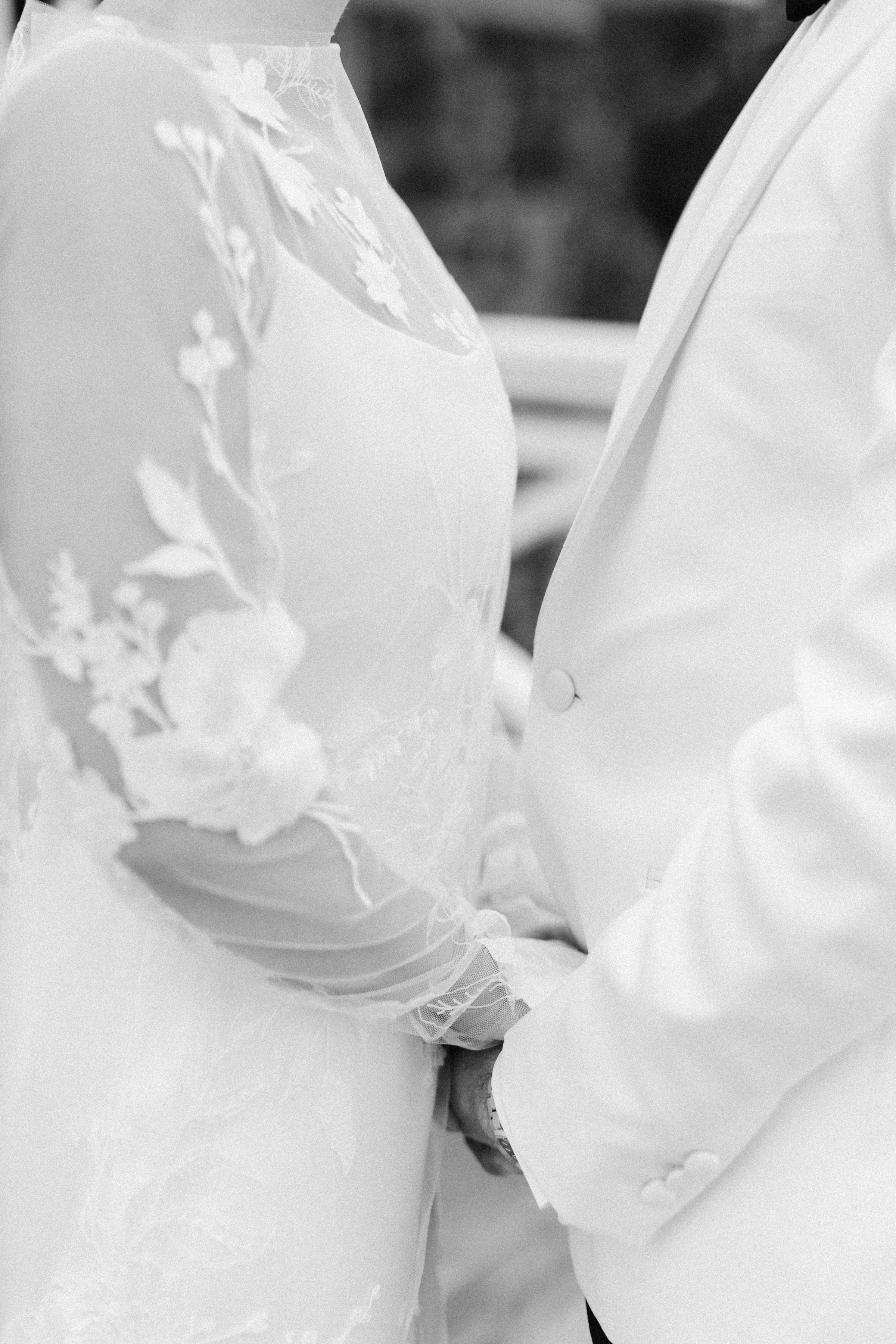 Close-up of a wedding couple kissing, with the bride wearing a lace dress and the groom in a white suit.