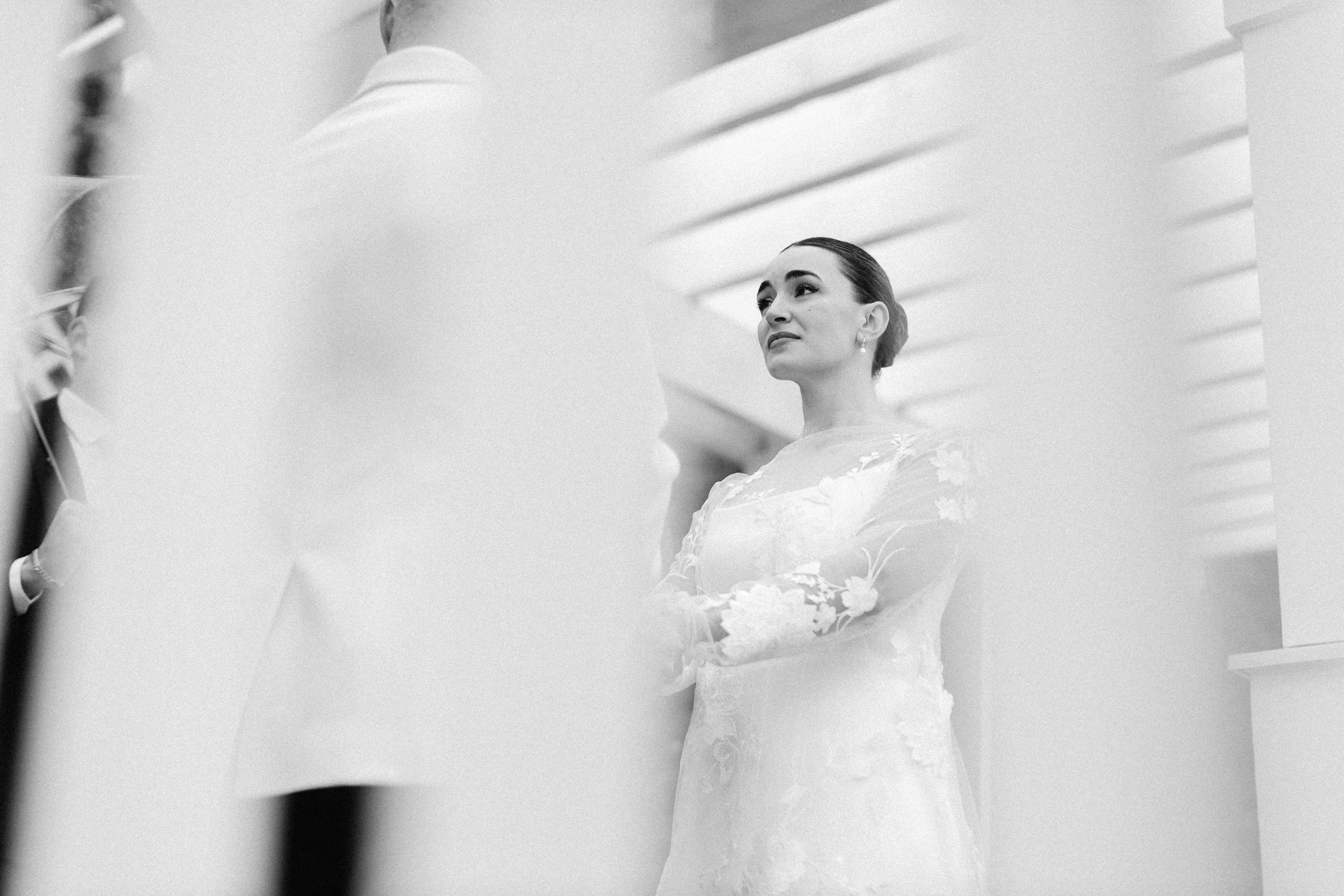 A woman in a wedding dress looking at her reflection in a mirror.