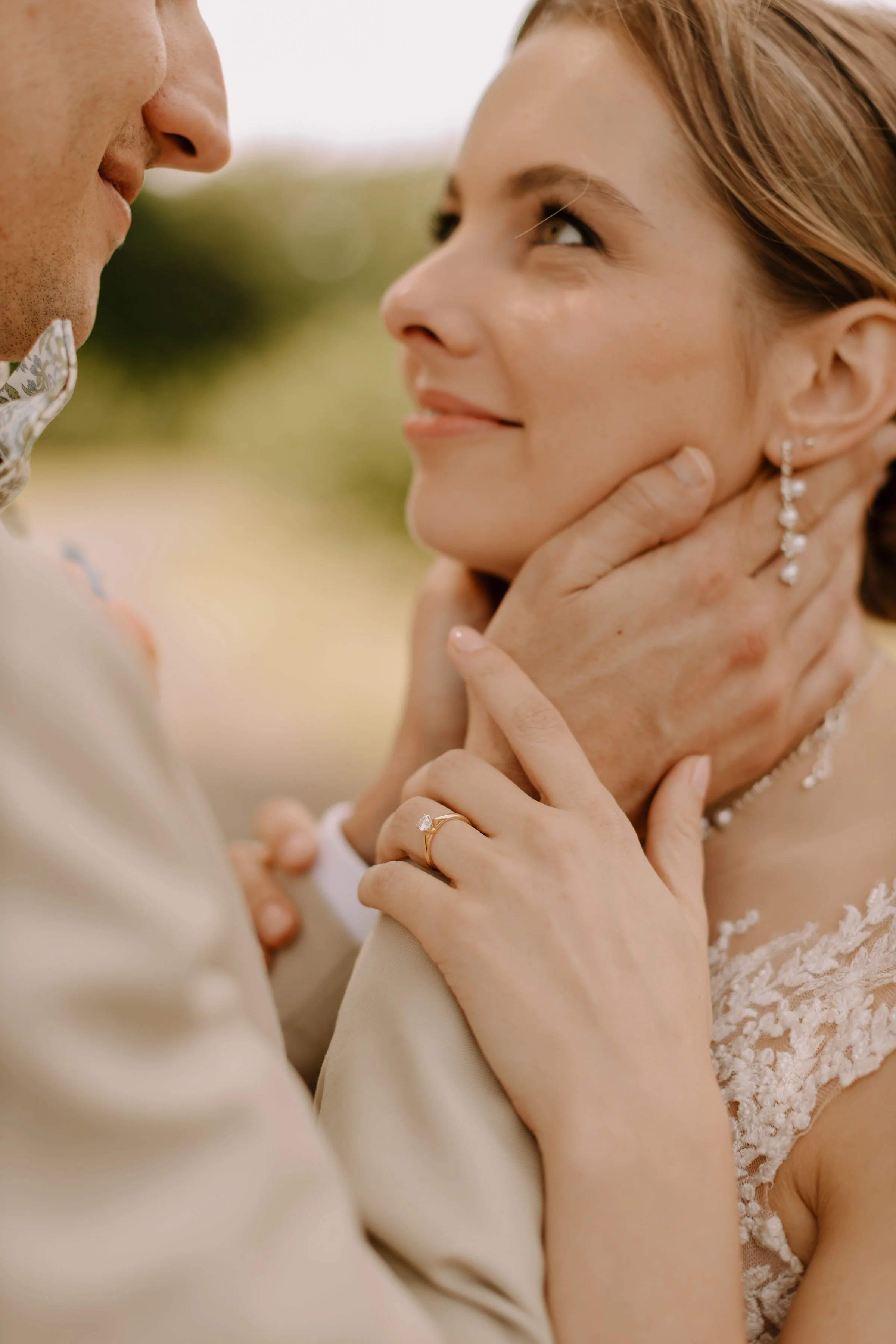Close-up of a couple holding each other's faces, gazing at each other during a wedding.