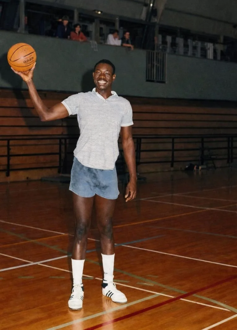 Mike Robinson, founder of Hidden Gems Scouting, holding a basketball in an indoor gymnasium in Paris, France.