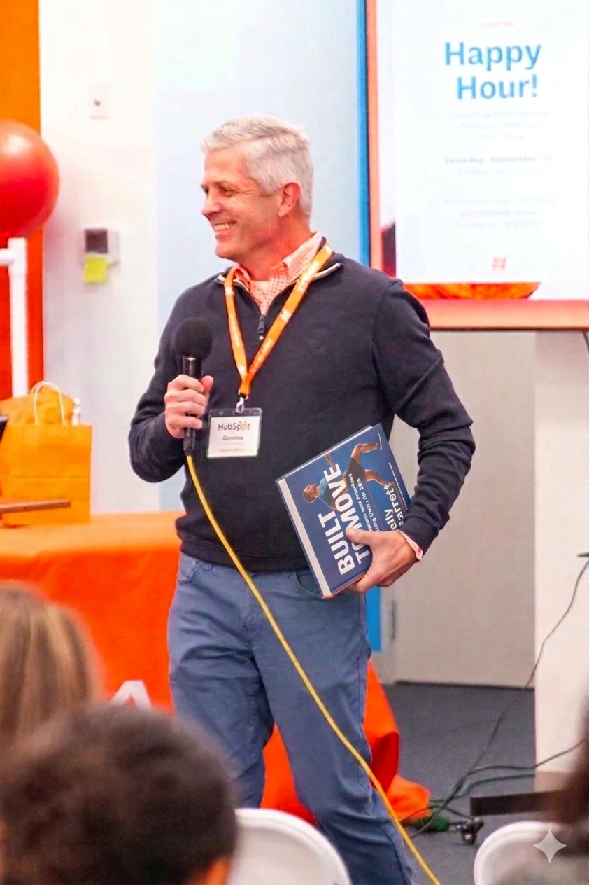 Jeff presenting at a health event, holding Built to Move book