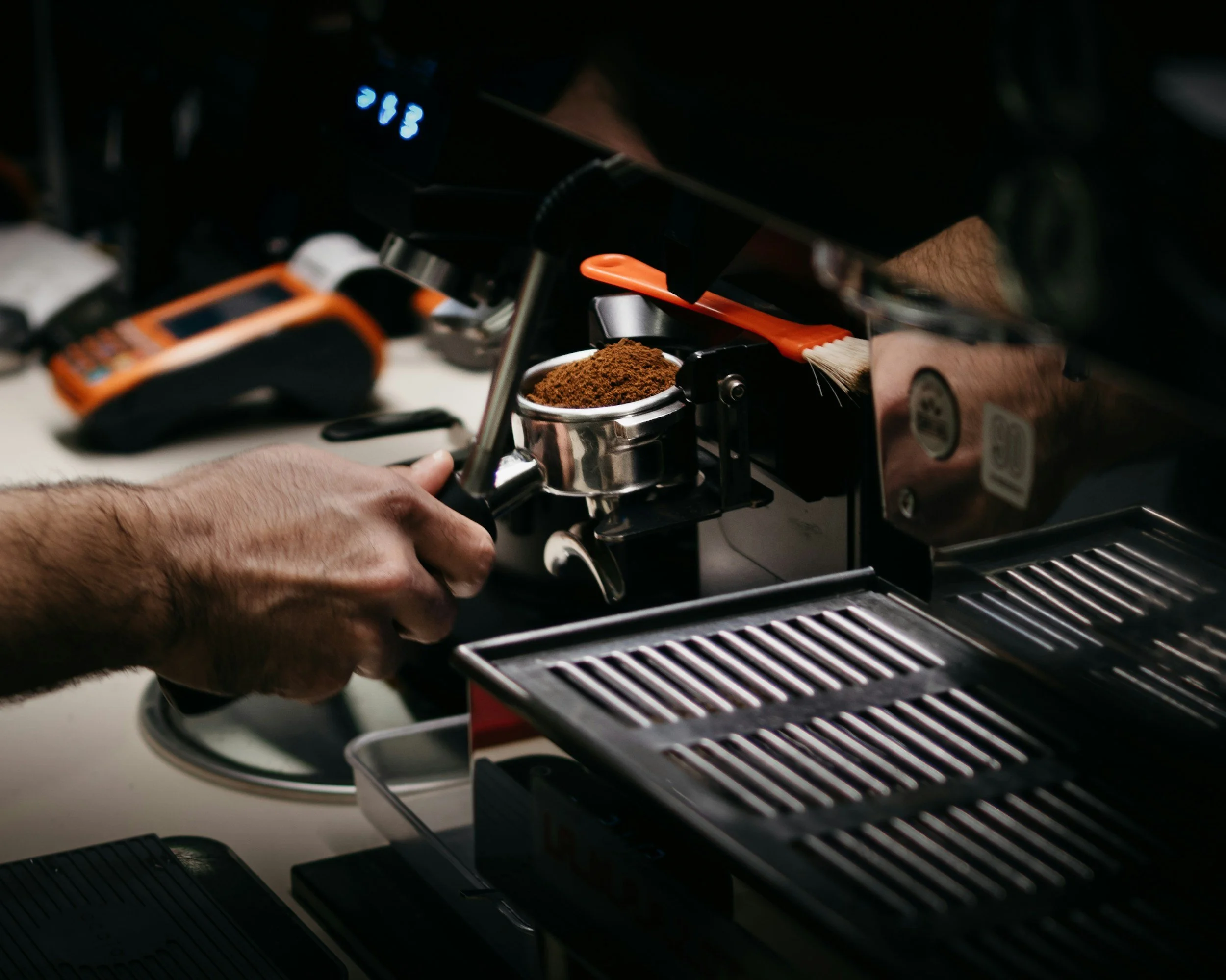 Barista preparing coffee using a coffee grinder on a coffee shop counter.