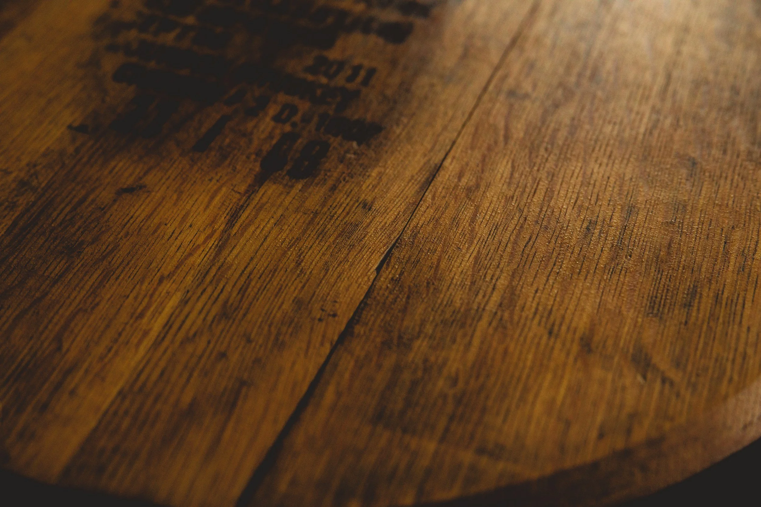 Close-up of a wooden surface with black stamped text that is partially visible.