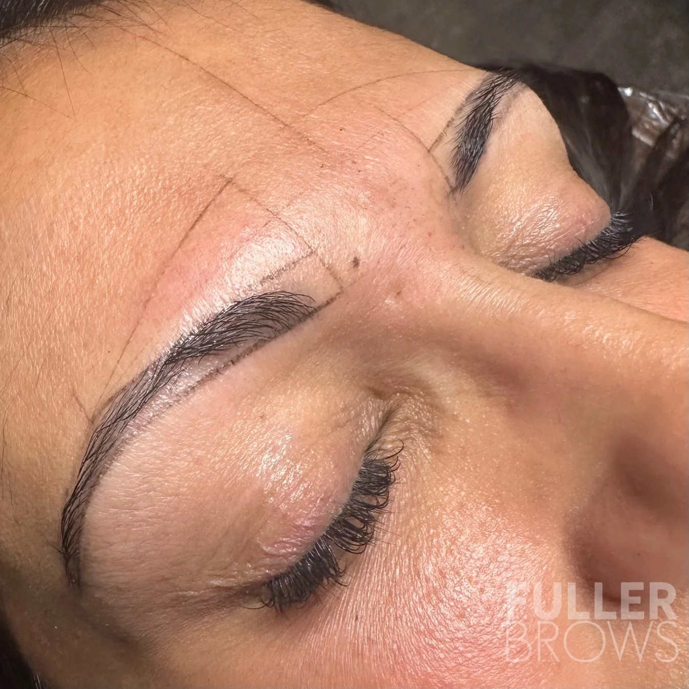Close-up of a person’s face with freshly microbladed eyebrows, showing makeup markings and outline for eyebrow shaping.