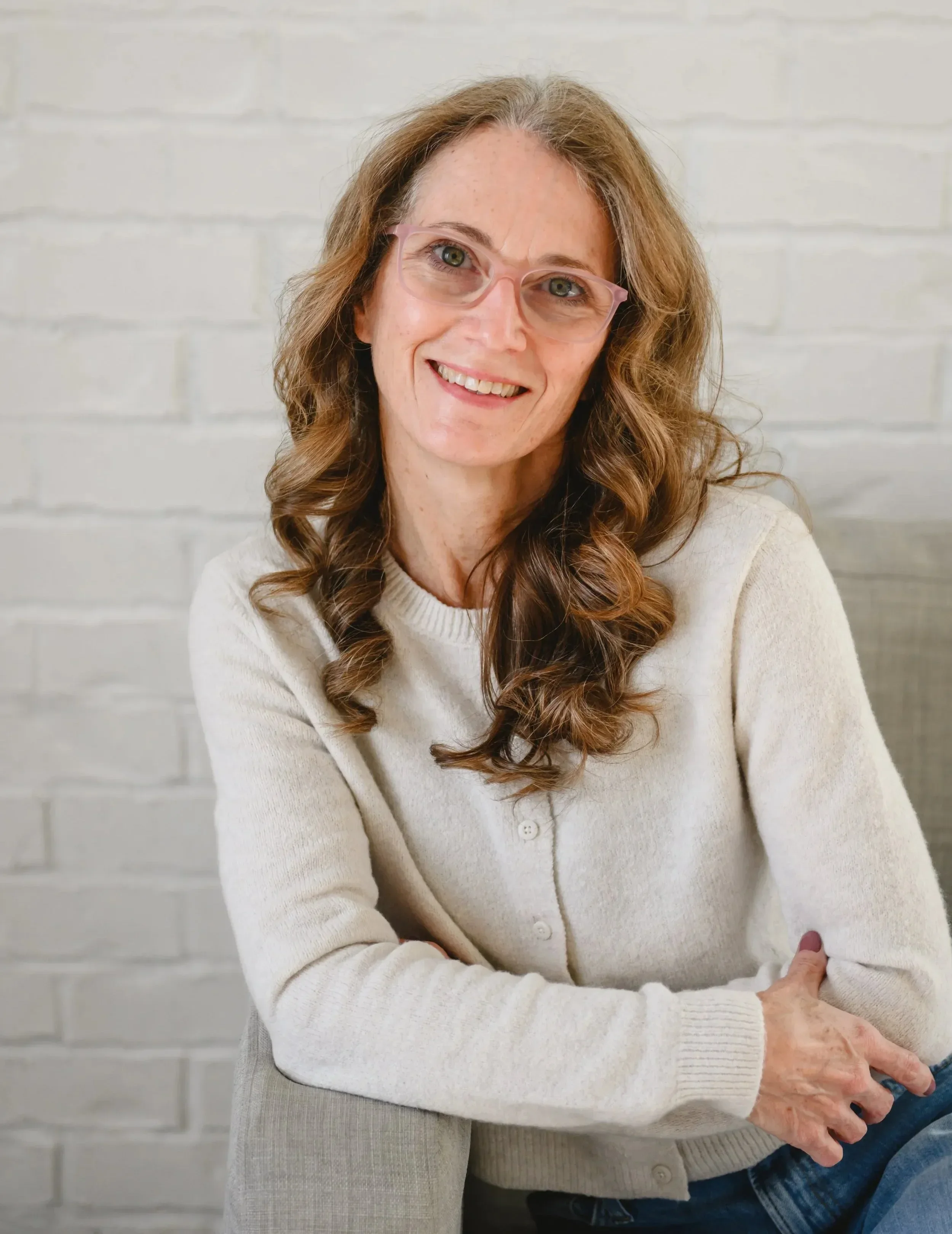 Dr. Servoss smiling in front of a white brick wall.