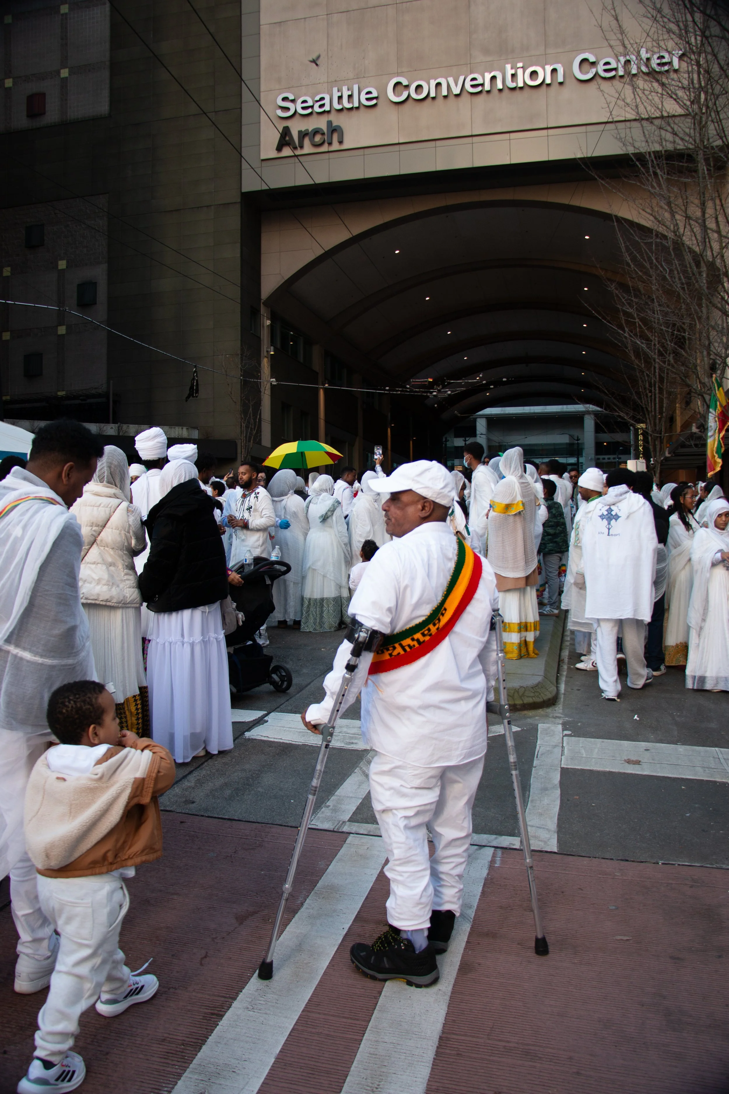 People dressed in white robes gather outside the Seattle Convention Center Arch during a public event.
