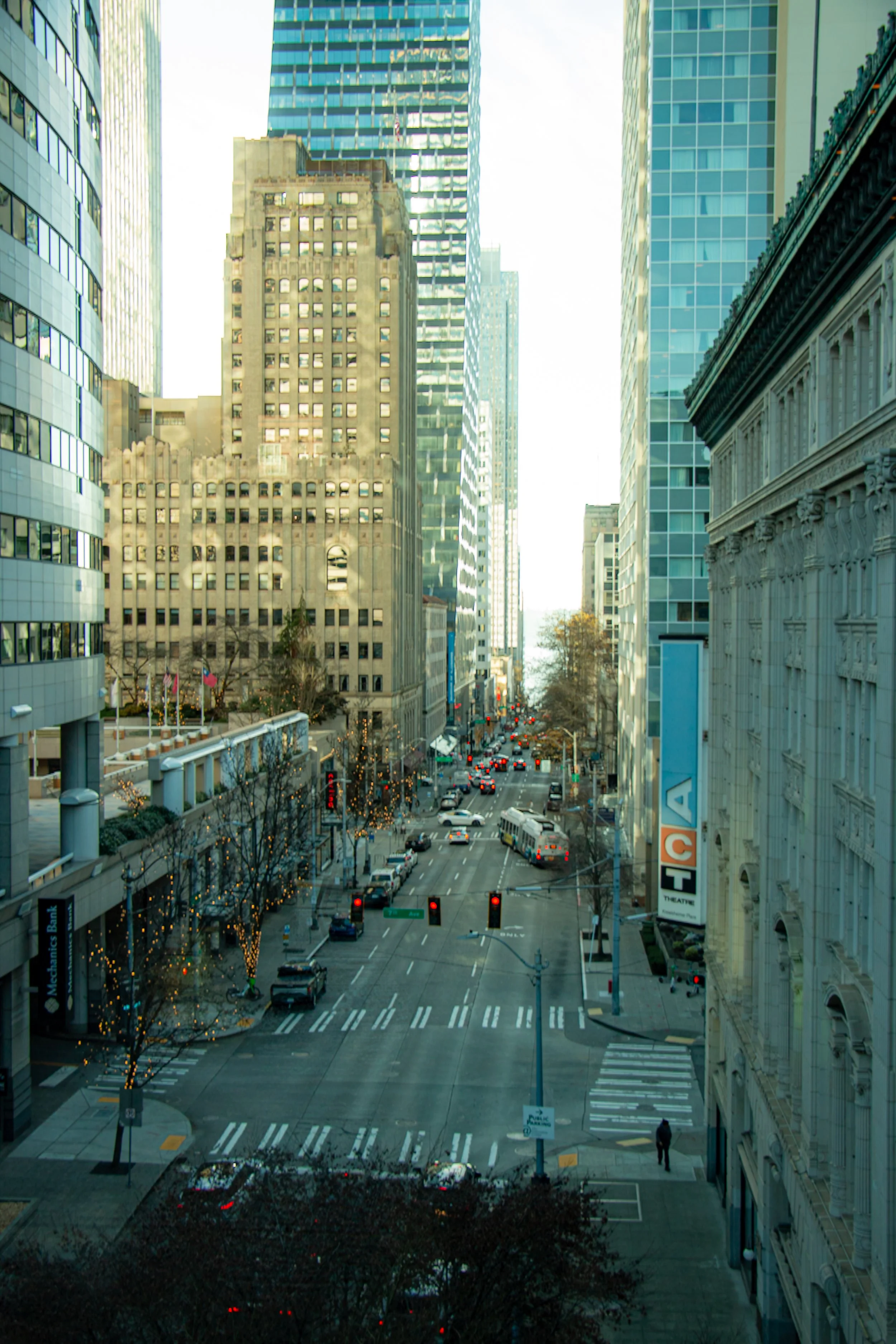 City street view with tall buildings, trees with string lights, cars, and a theater sign in the foreground.