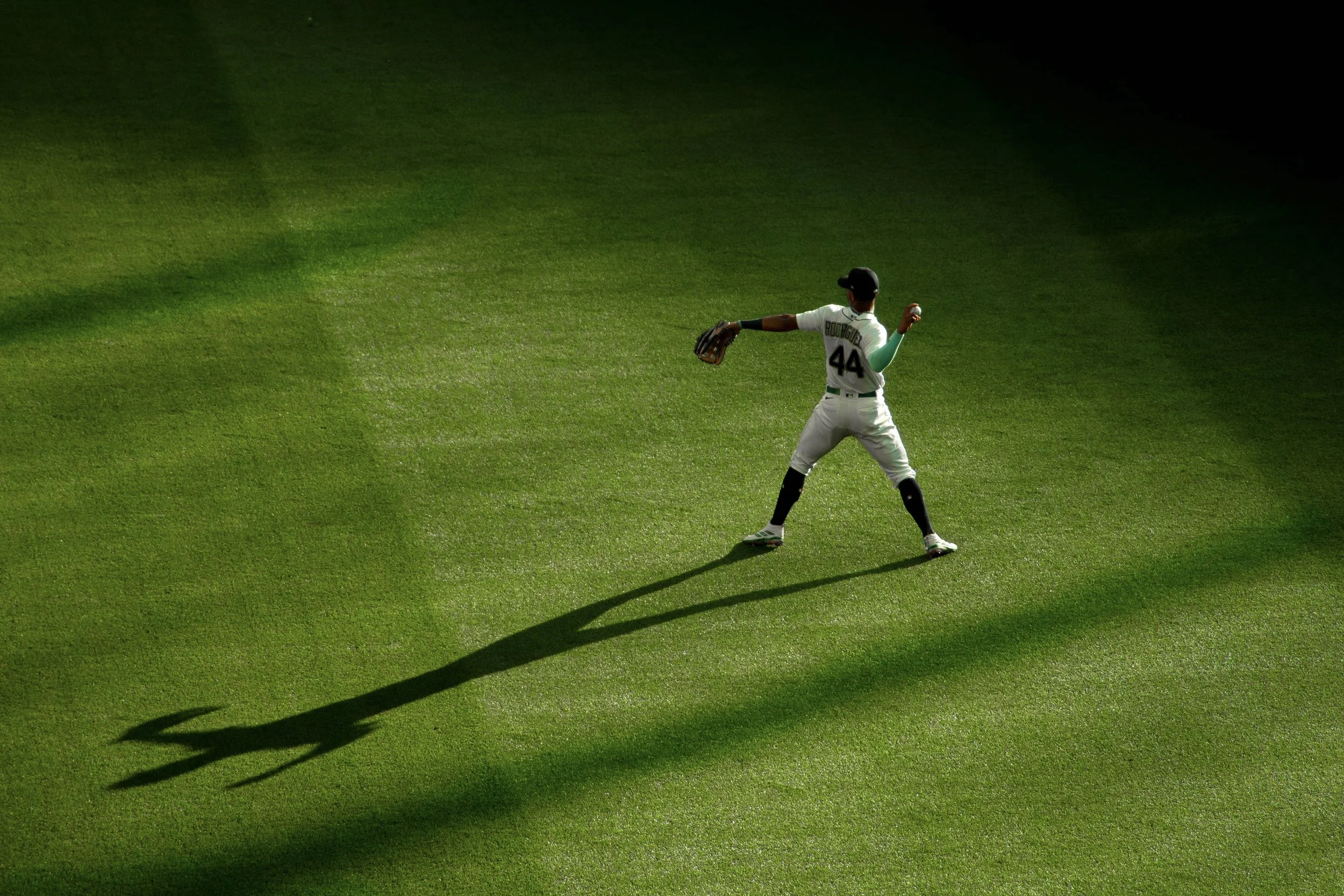 A baseball player wearing a uniform with the number 44 prepares to catch a ball on a green grass field.