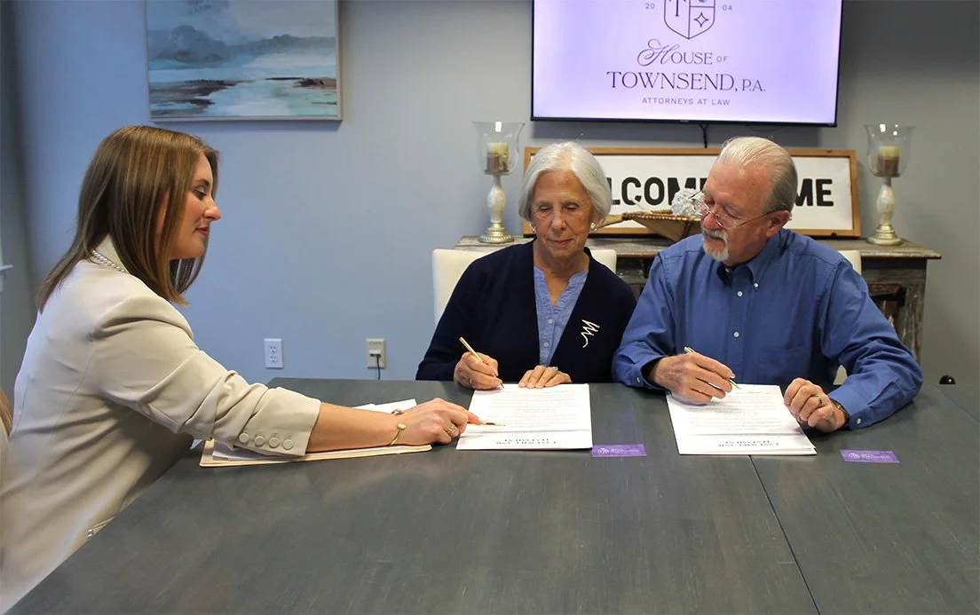Veronica Townsend slightly reaching across table while point at documents as clients follow along
