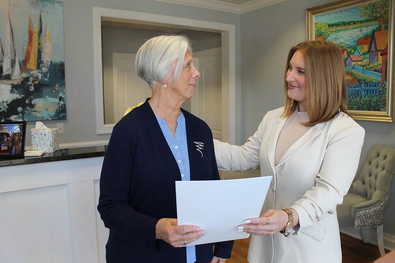 Veronica Townsend comforting clients with a soft smile while handing over a document