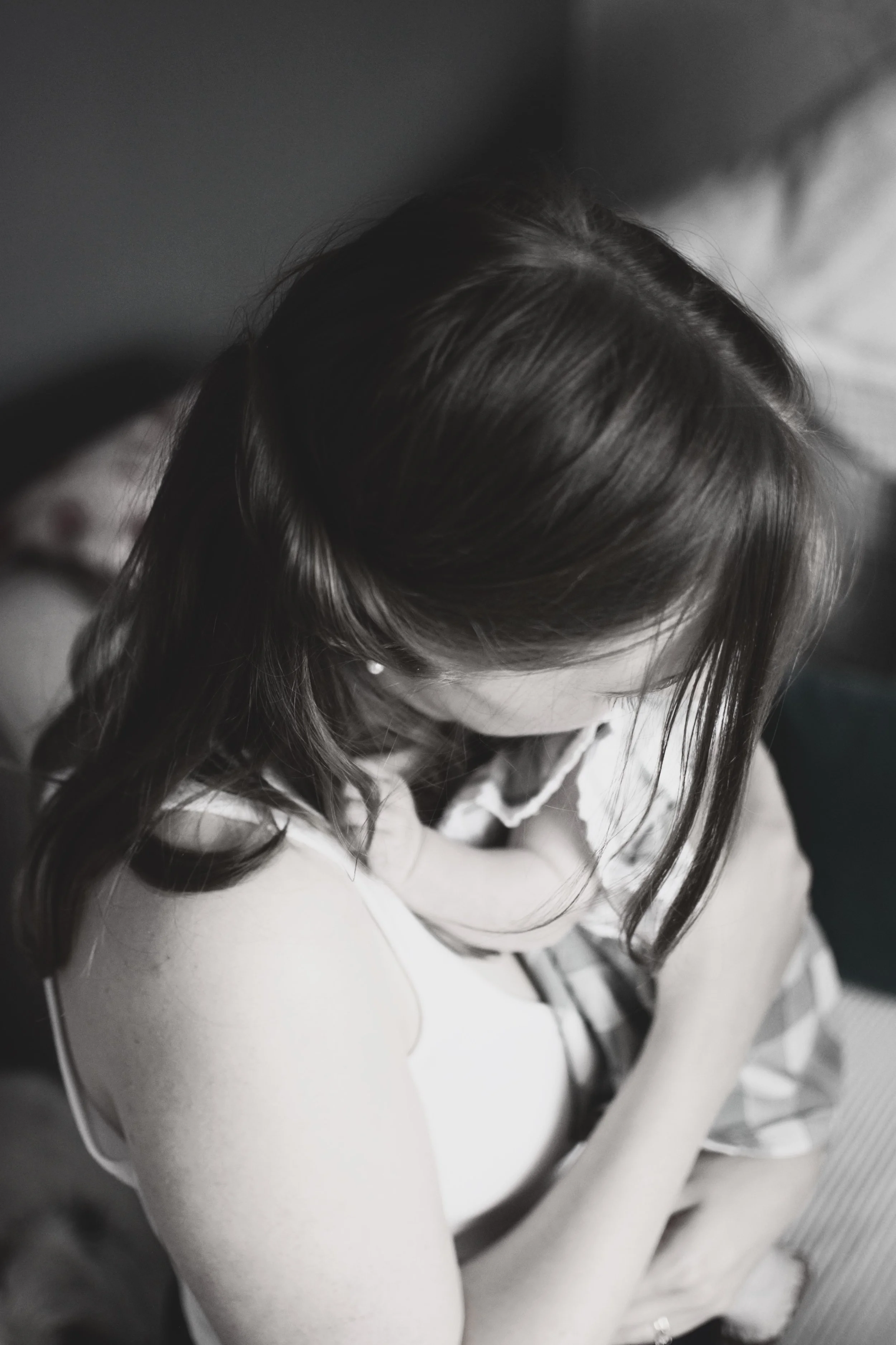 A black-and-white photo of a woman sitting with her head bowed, her hair covering her face.