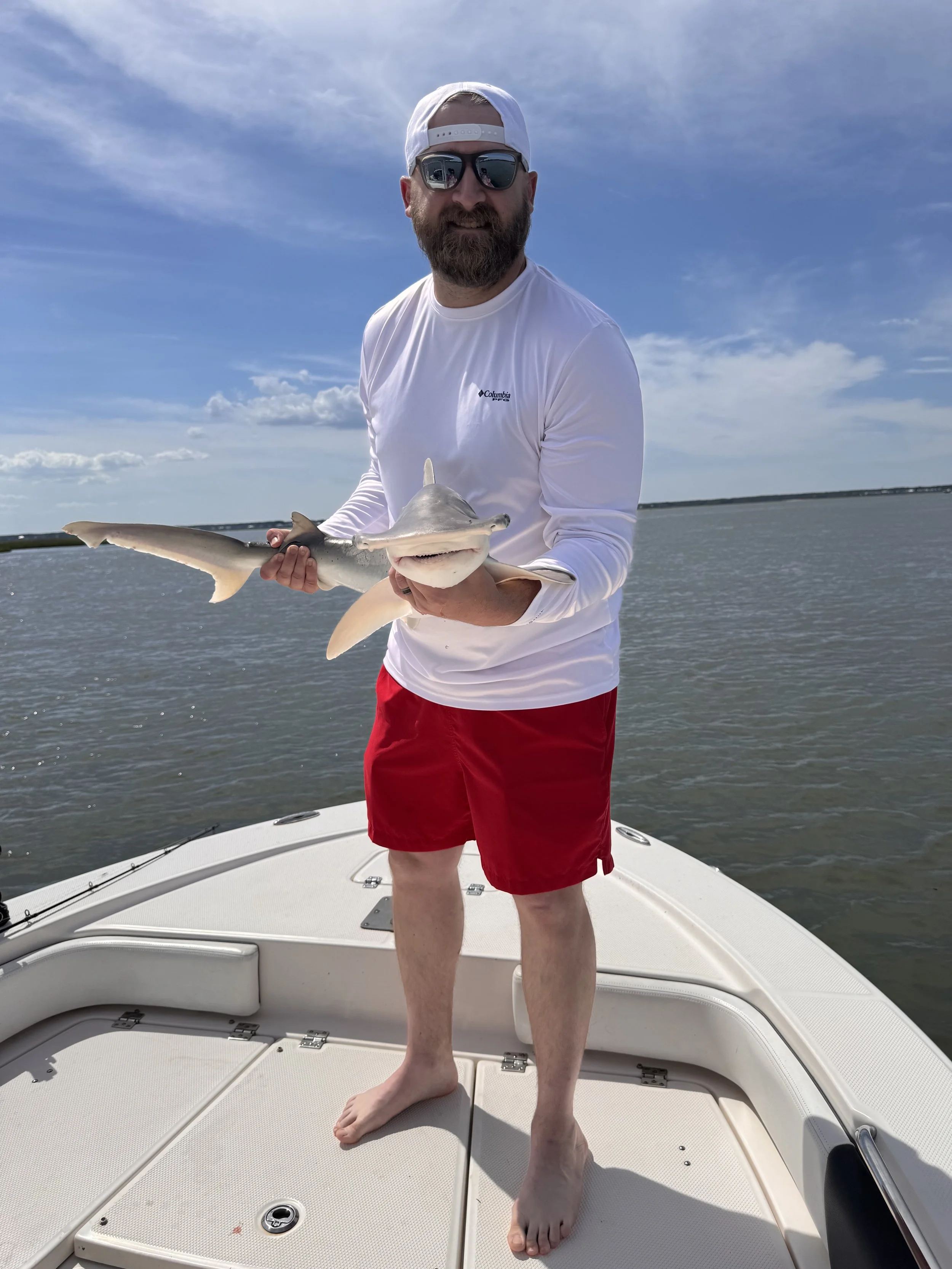 Matthew Walz, Senior Accountant at Walz & Co Accounting standing on a boat holding a shark that he just caught with his family
