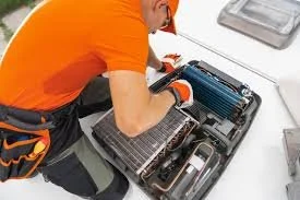 Person repairing a computer motherboard with tools on a white work surface.