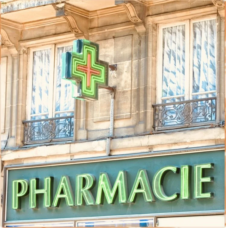Neon sign for a pharmacy on a building facade, with the word 'PHARMACIE' in green lights and a green and red cross symbol above.