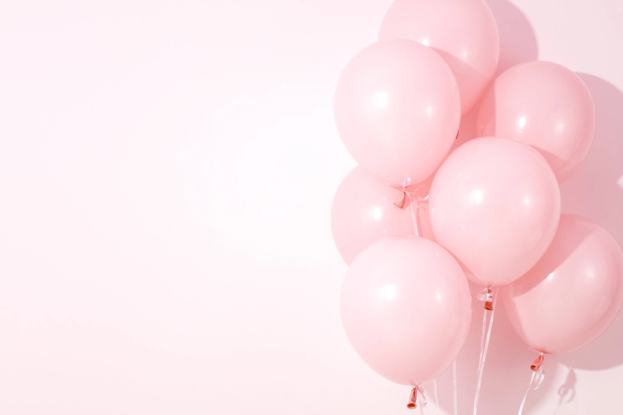 Pink balloons clustered together against a light pink background.