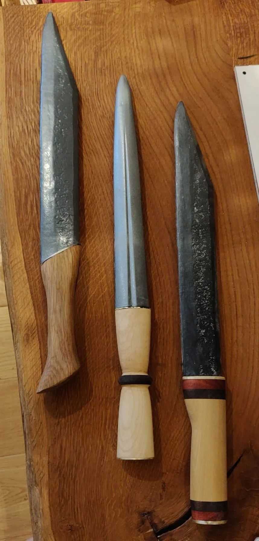 Drei Messer auf einem Holz Tisch, die-in der Mitte ein Küchenmesser, das andere Messer sind größer