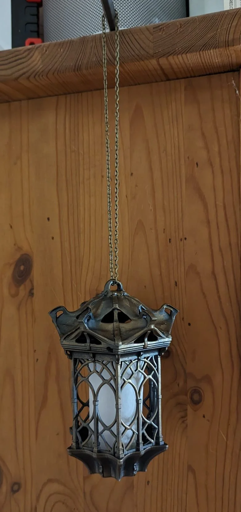 Hängende, alte Laterne mit Metallrahmen an einer Holzdecke.