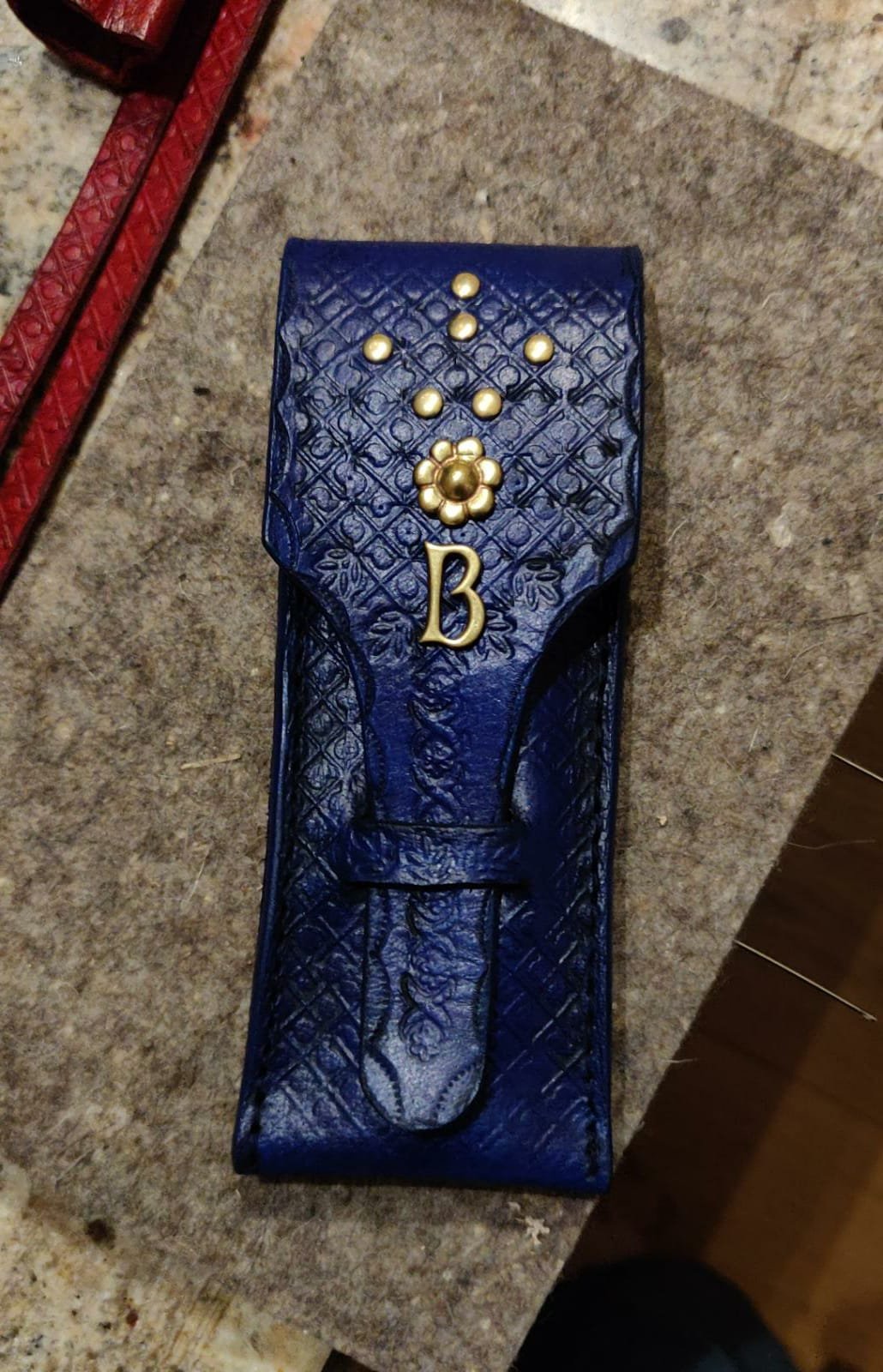 Ein blauer, dekorativer Koffer mit goldenen Verzierungen und einem Buchstaben 'B' darauf, liegt auf einer Steinoberfläche.