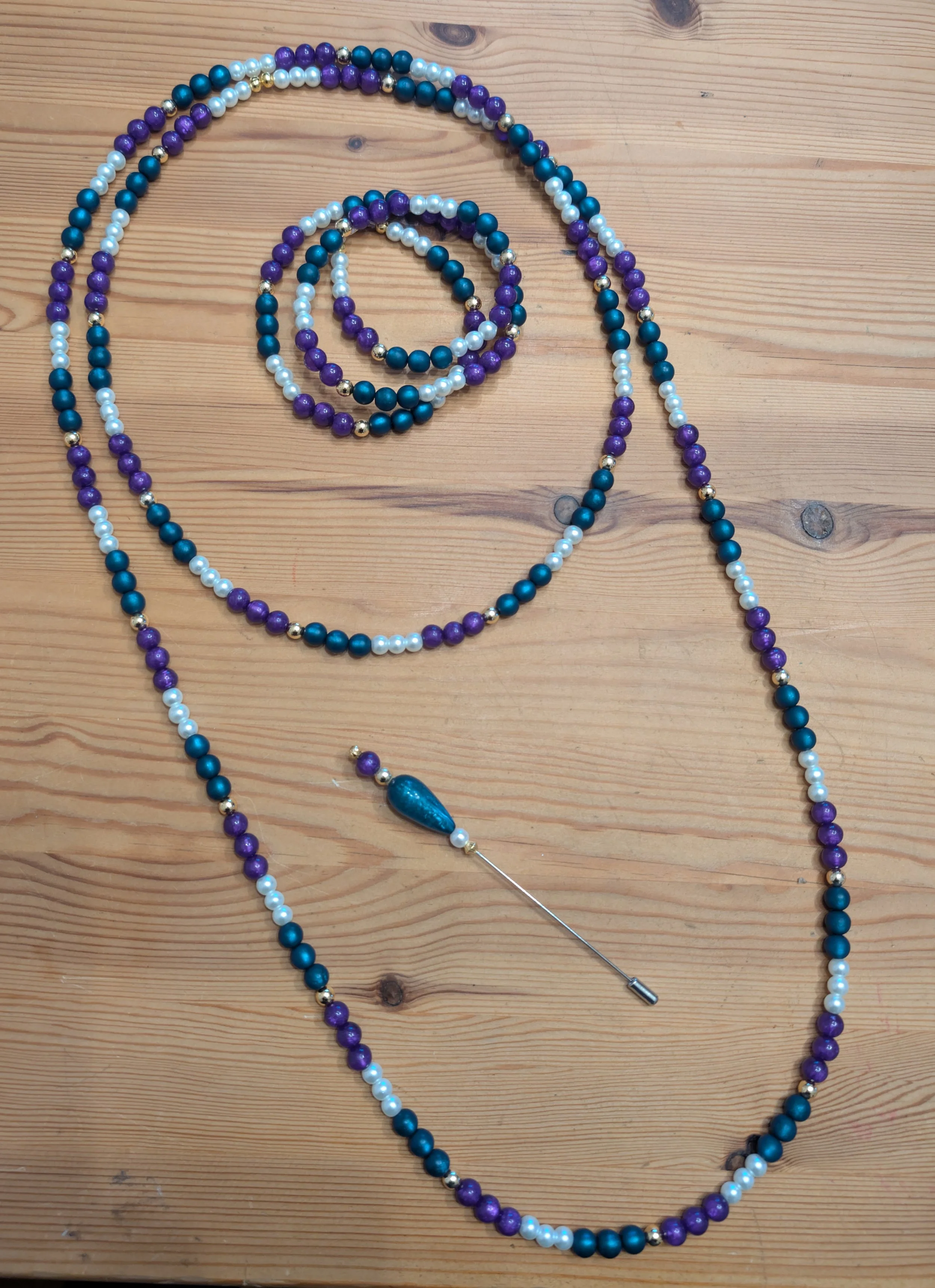 Perlenkette und Brosche auf einem Holztisch.