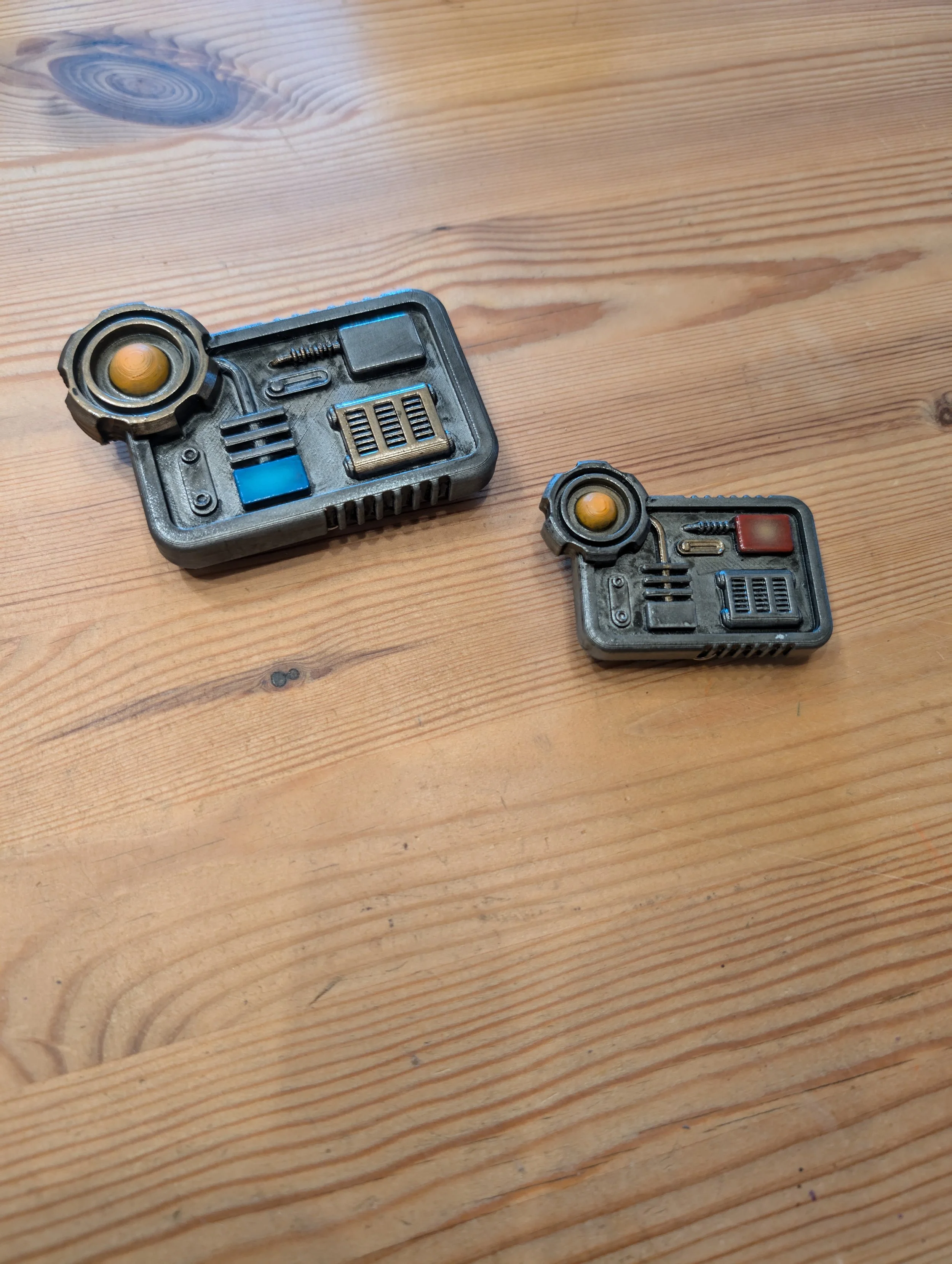 Zwei kleine Propeller mit gelben und orangefarbenen Zentren, die auf einer Holztischfläche liegen, im Retro-Design, vielleicht Spielzeug oder Modellteile.