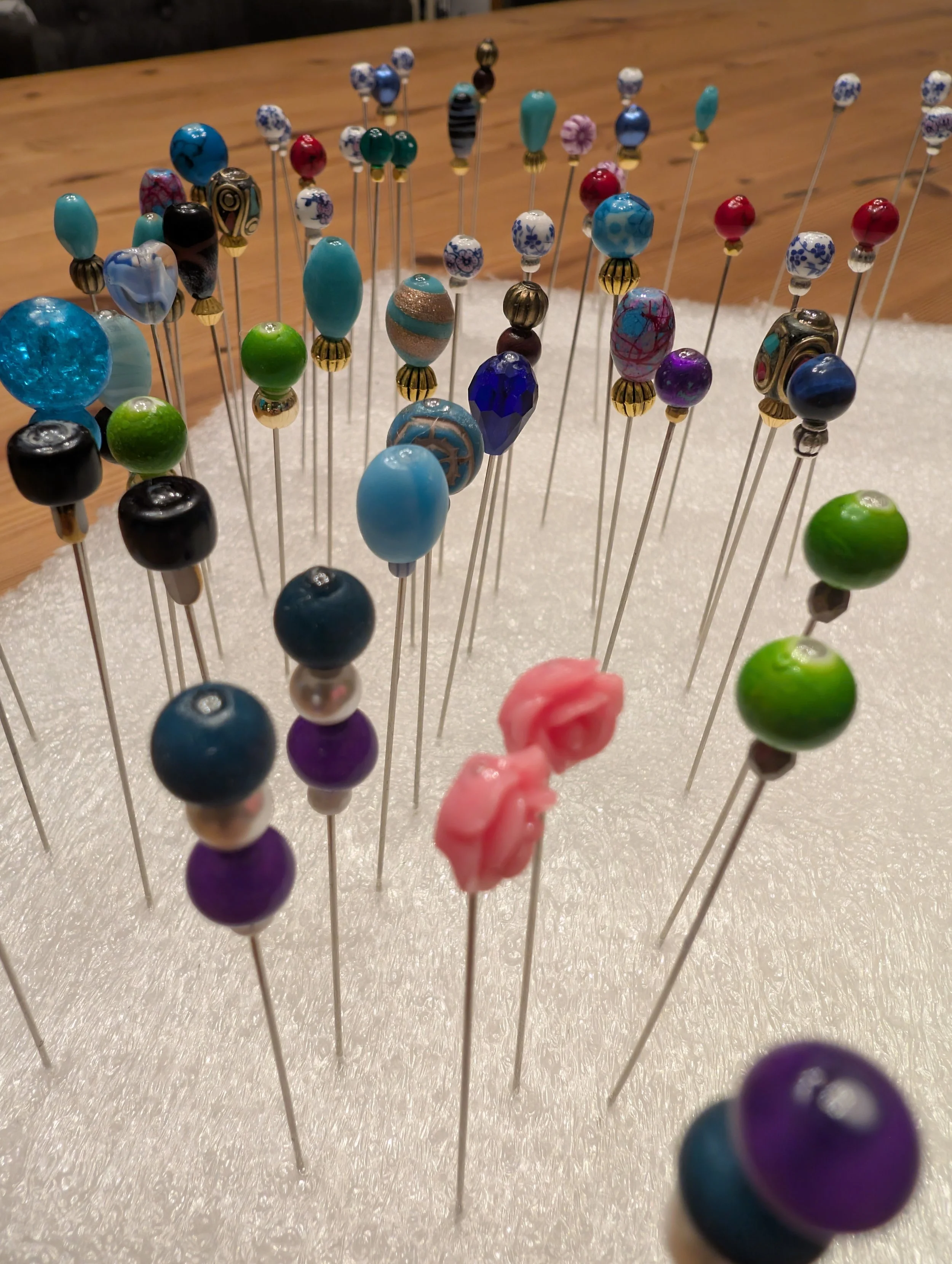 Bunte Perlen auf Nadeln in einer weißen Vlies