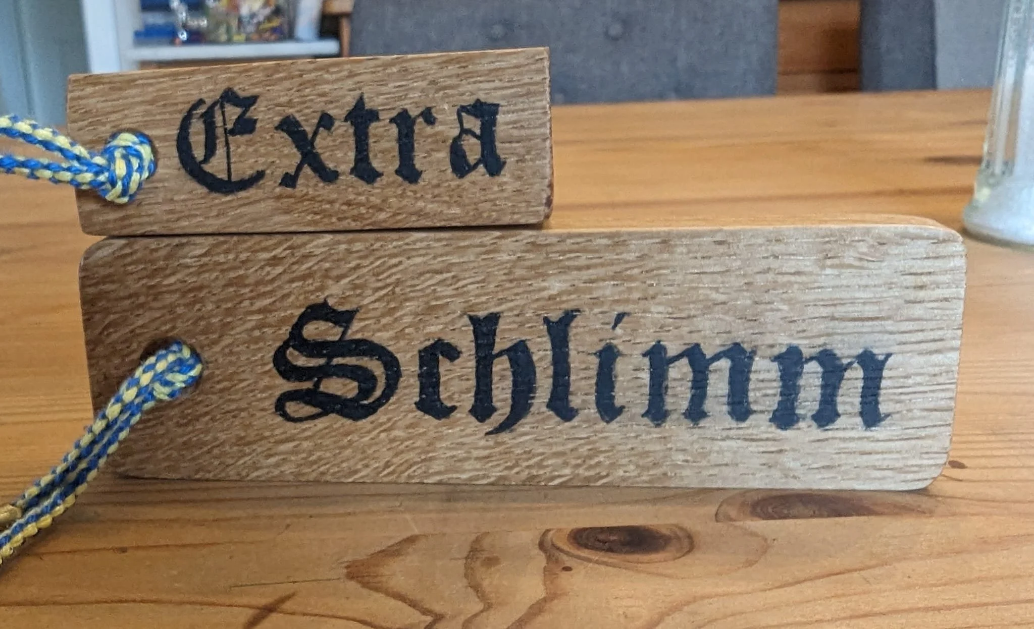 Zwei Holzkärtchen mit den schwarzen Schriftzügen "Extra" und "Schlimm" auf einem Holztisch.