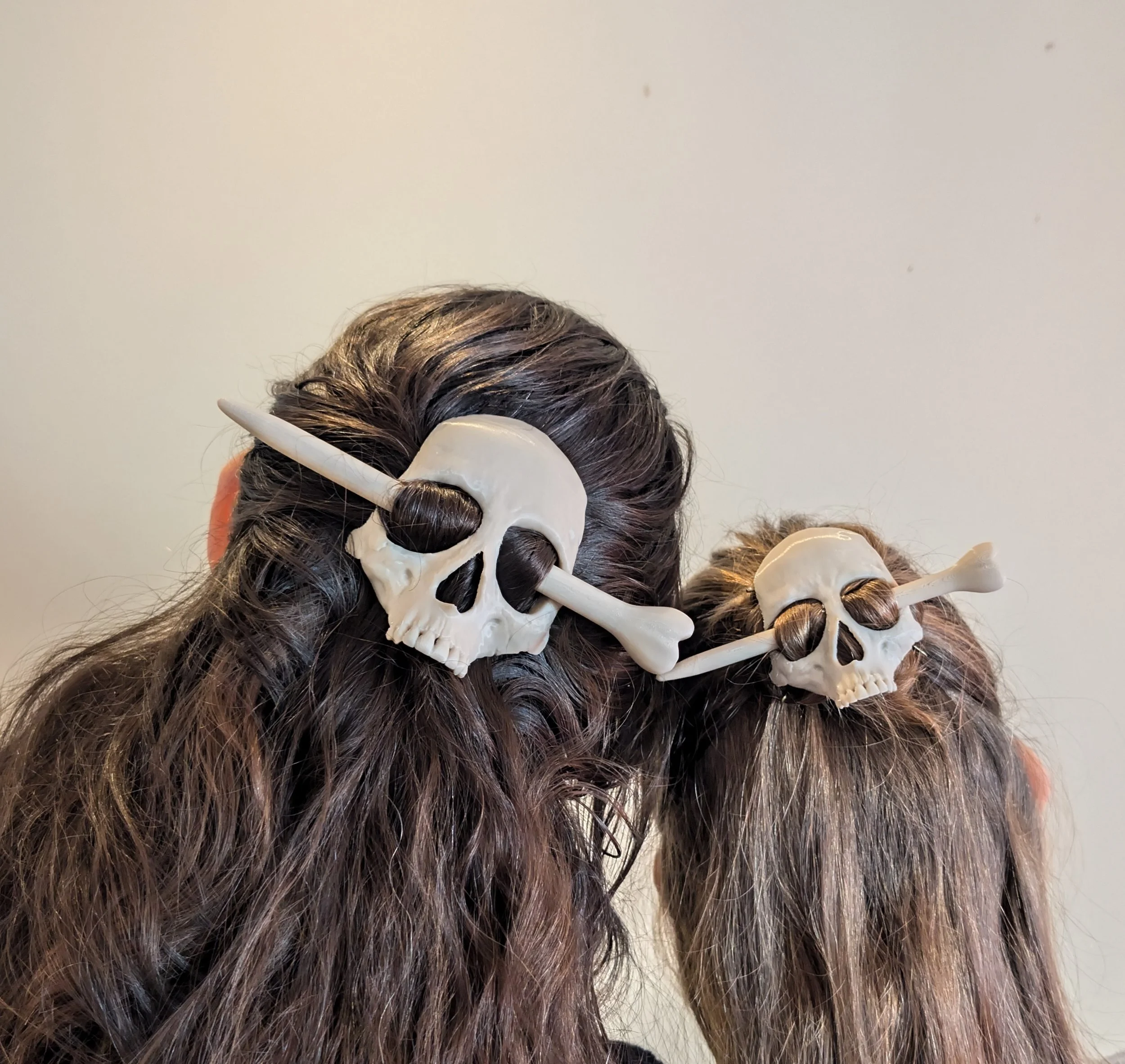 Zwei Menschen tragen Filzhauben mit Skull-Designs und eingebauten Knochen, die wie Horror-Accessoires aussehen.