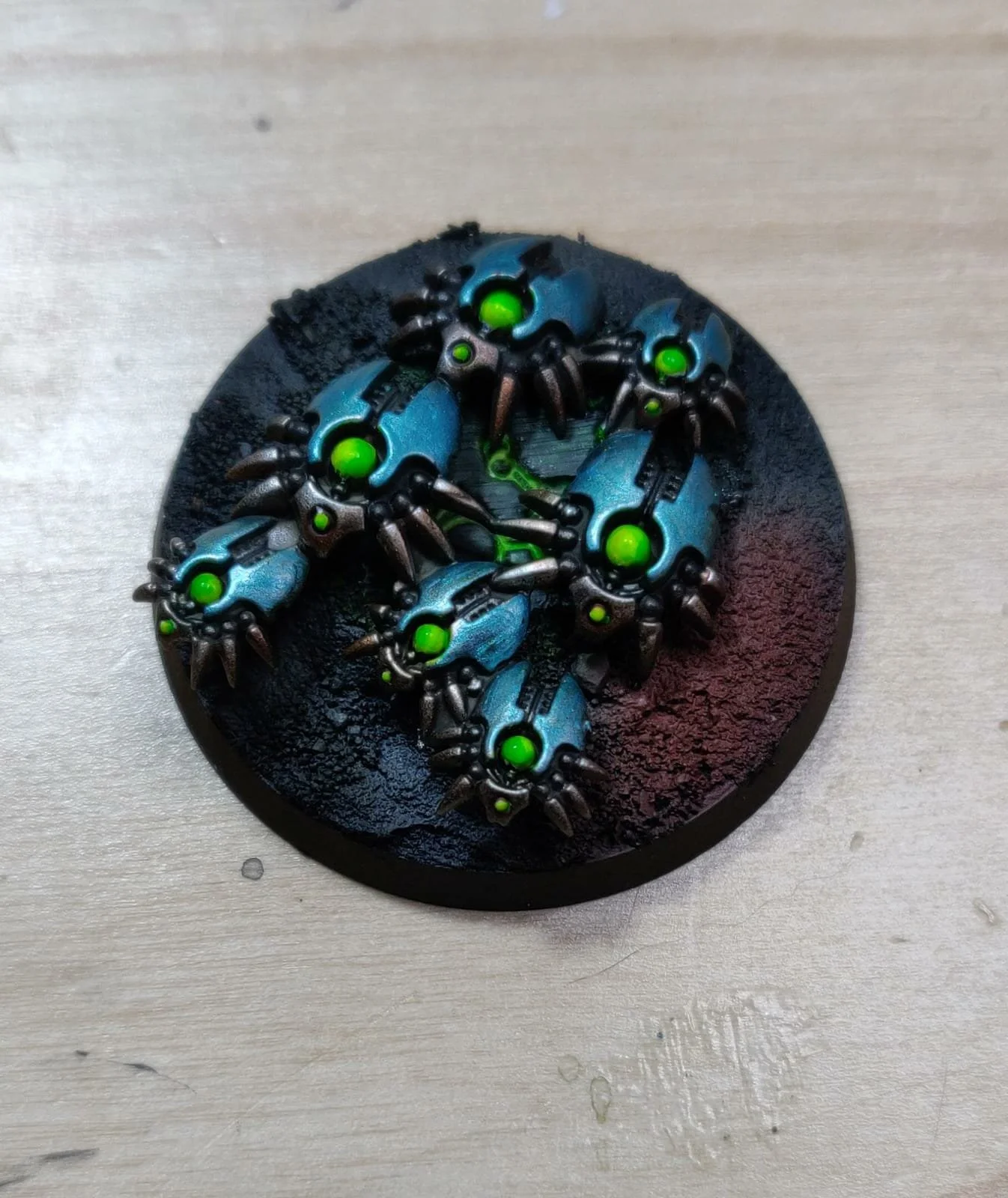 Miniaturmodelle von mechanischen Kreaturen mit blauen Gehäusen und grünen Zentren auf einem schwarzen basierten Untergrund.