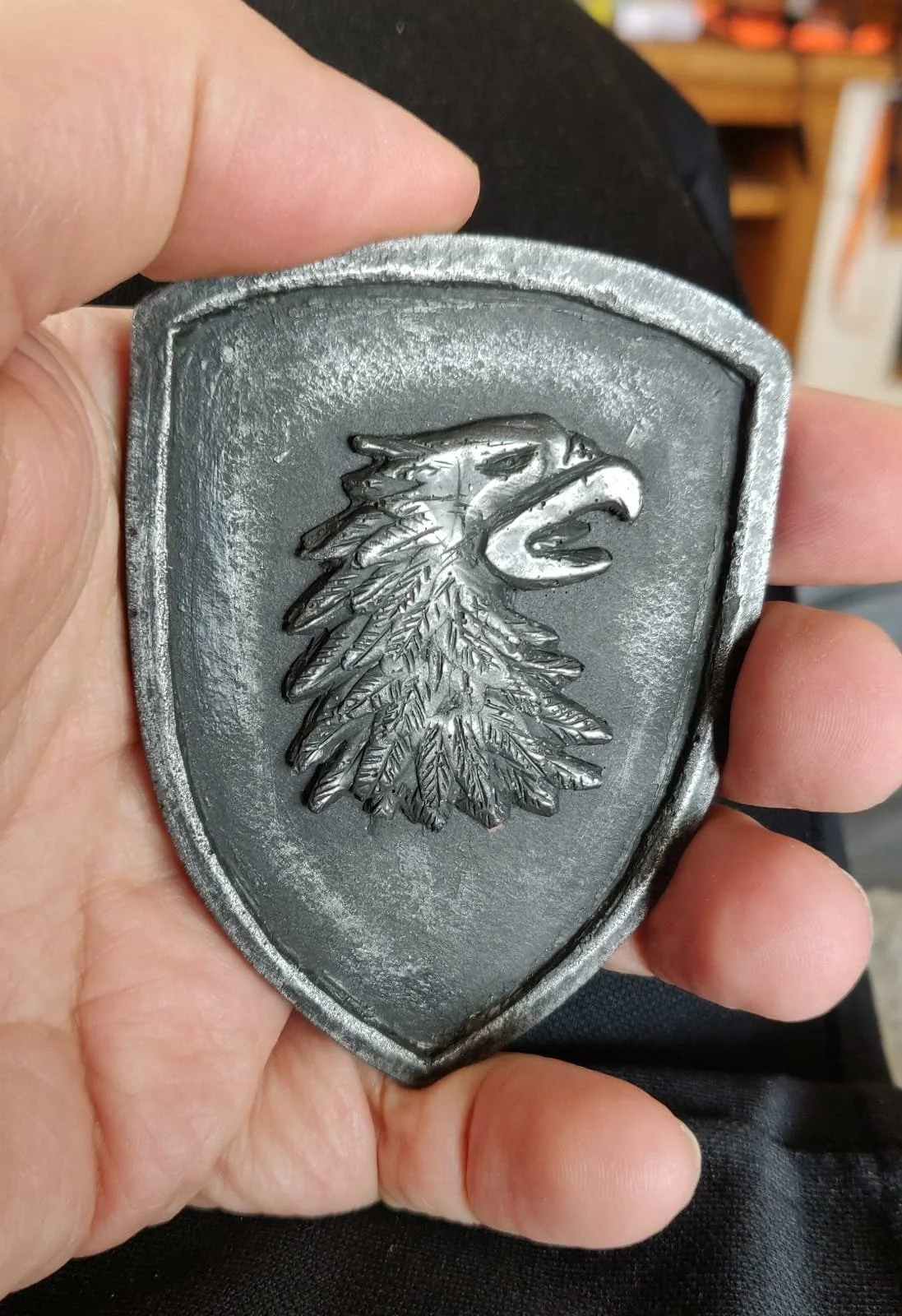 Eine metallene Abzeichen mit einem Adlerkopf und einem Baum, typisch für die deutsche Polizei.