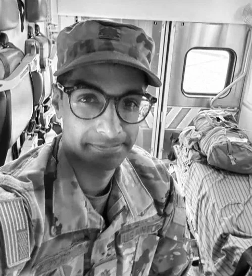A soldier in uniform taking a selfie on a bus, with bags and other supplies in the background.