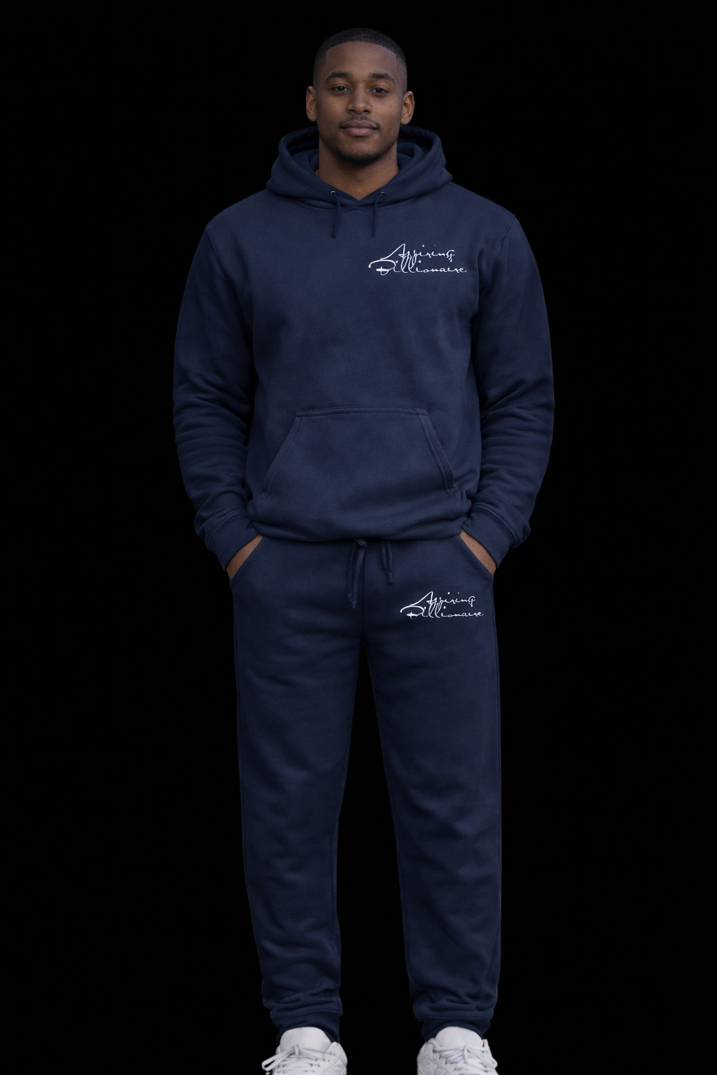 A young man wearing a navy blue hoodie and sweatpants with white writing, standing against a black background.