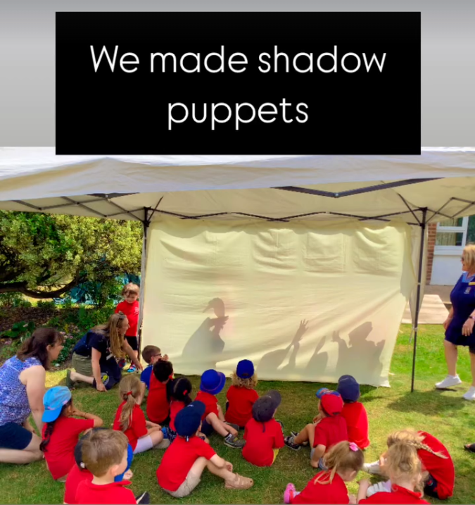 Children watching shadow puppet show under a tent with a backdrop showing shadow puppets on it.