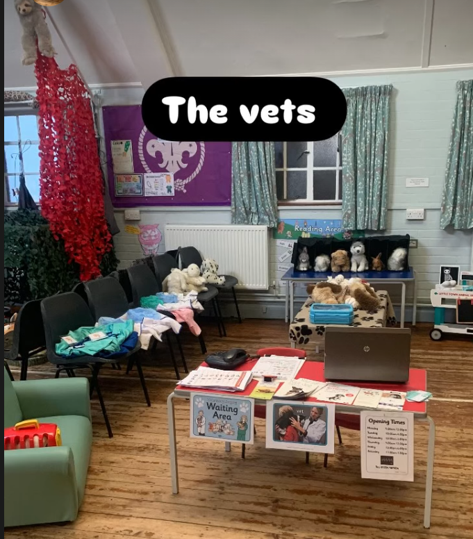 Room set up for vet clinic with chairs, stuffed animals, and informational signs about the waiting area and opening times.