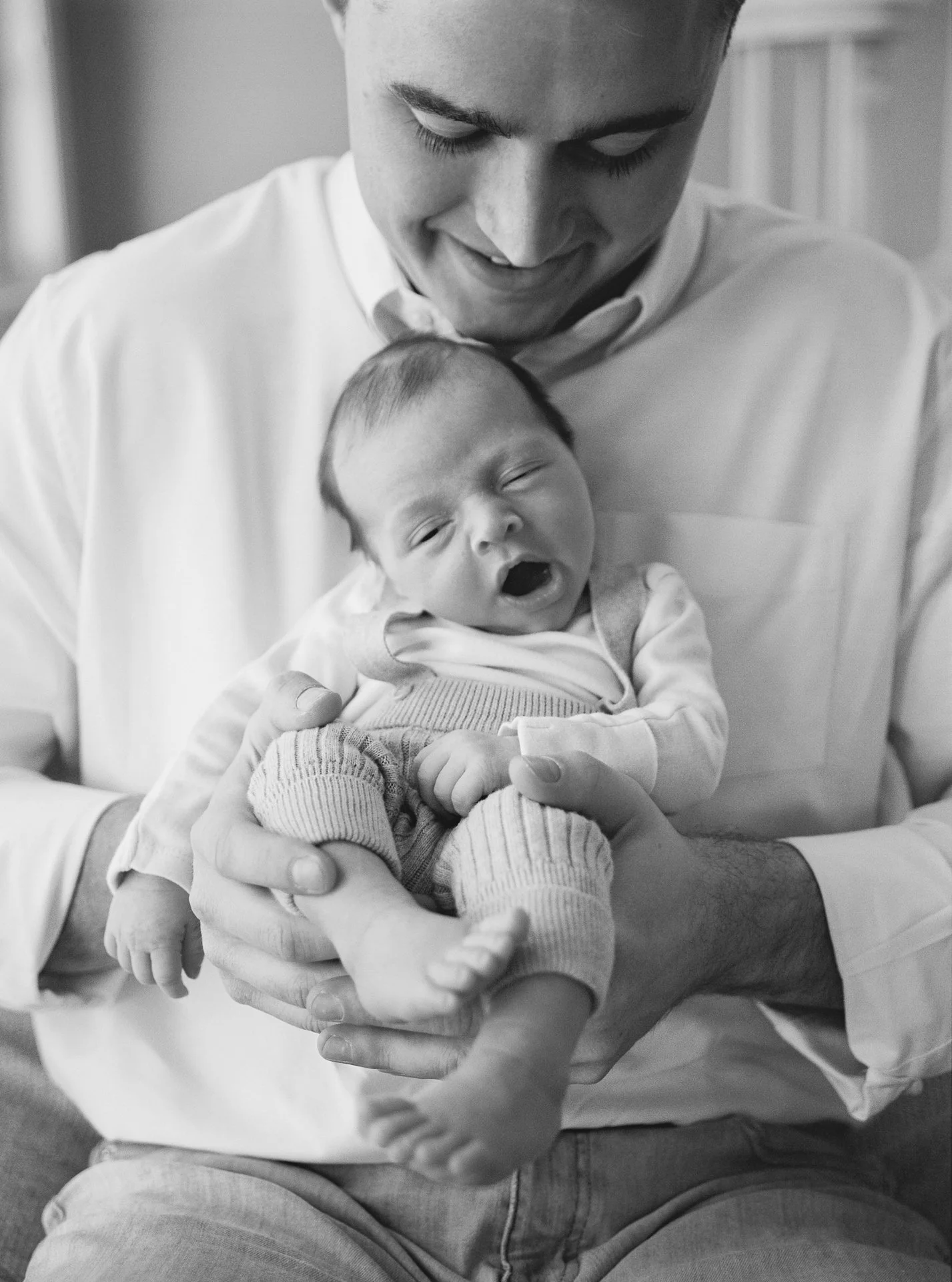 A man holding a yawning baby.