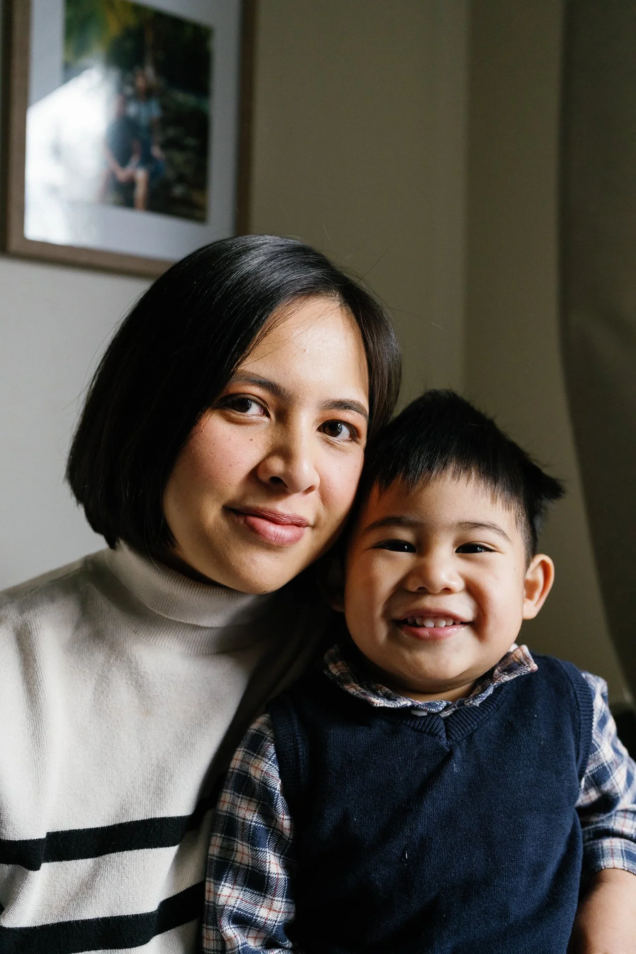 Close-up of a woman and a young boy smiling together indoors.
