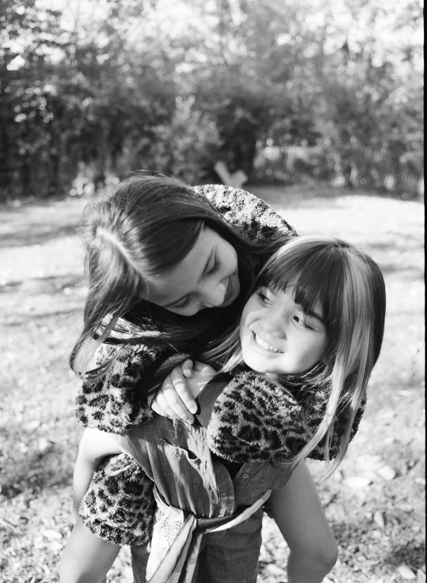 A woman and a girl are hugging outdoors, smiling at each other.