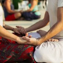 Close-up of hands holding a small object during a massage or healing session in a clinical environment.