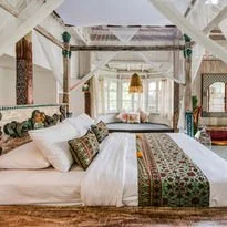 A bedroom with a four-poster bed, white linens, and decorative pillows.