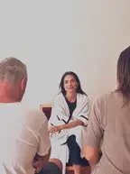 A woman talking to two men in a casual indoor setting.